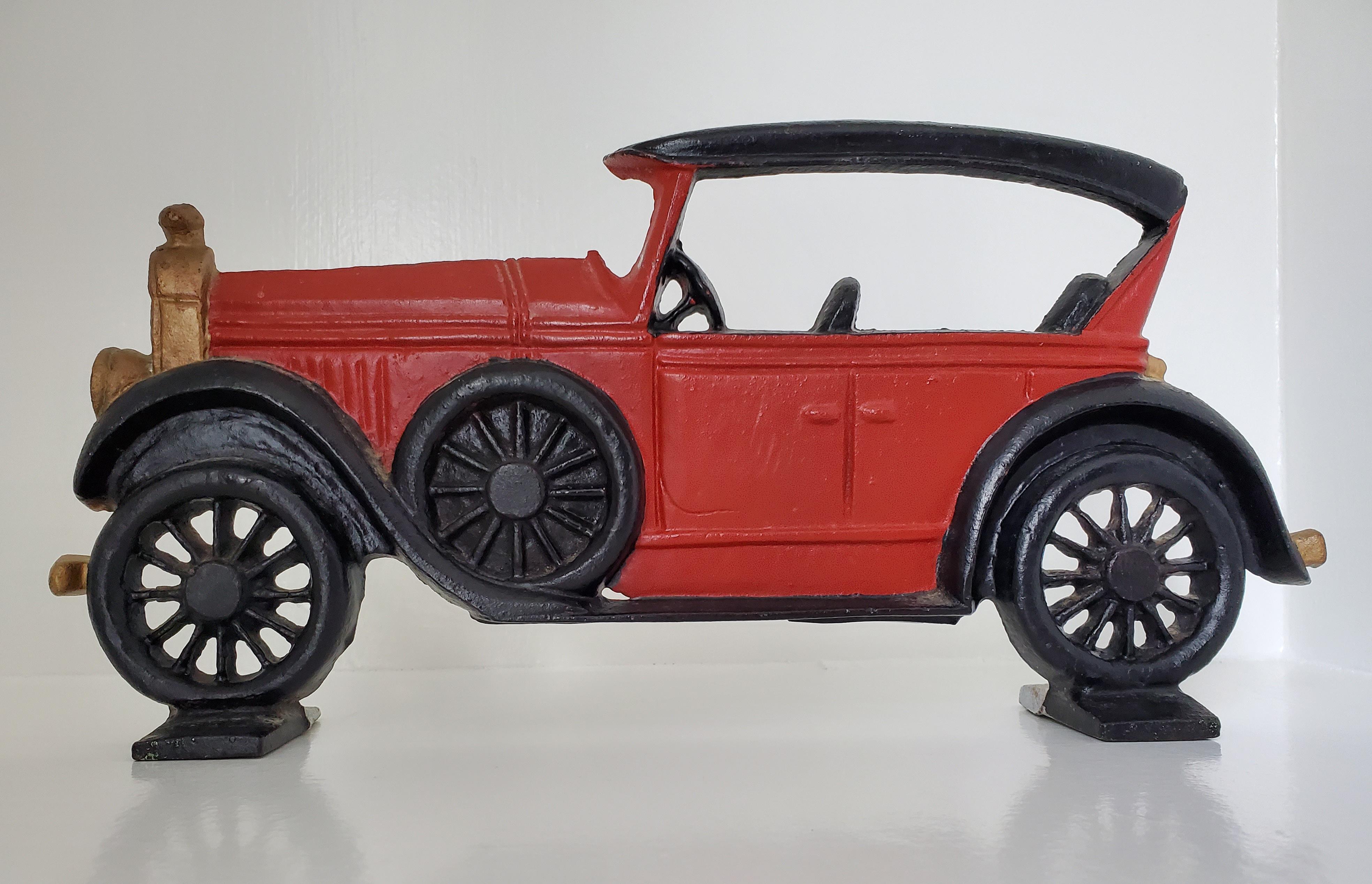 This fabulous pair of painted cast iron antique cars can be used as door stops, book ends, or shelf décor. One is a red, early Model T Ford with gold and black accents. it weighs 1481 grams and is 13 inches long, 6 inches high, and 2.5 inches wide.