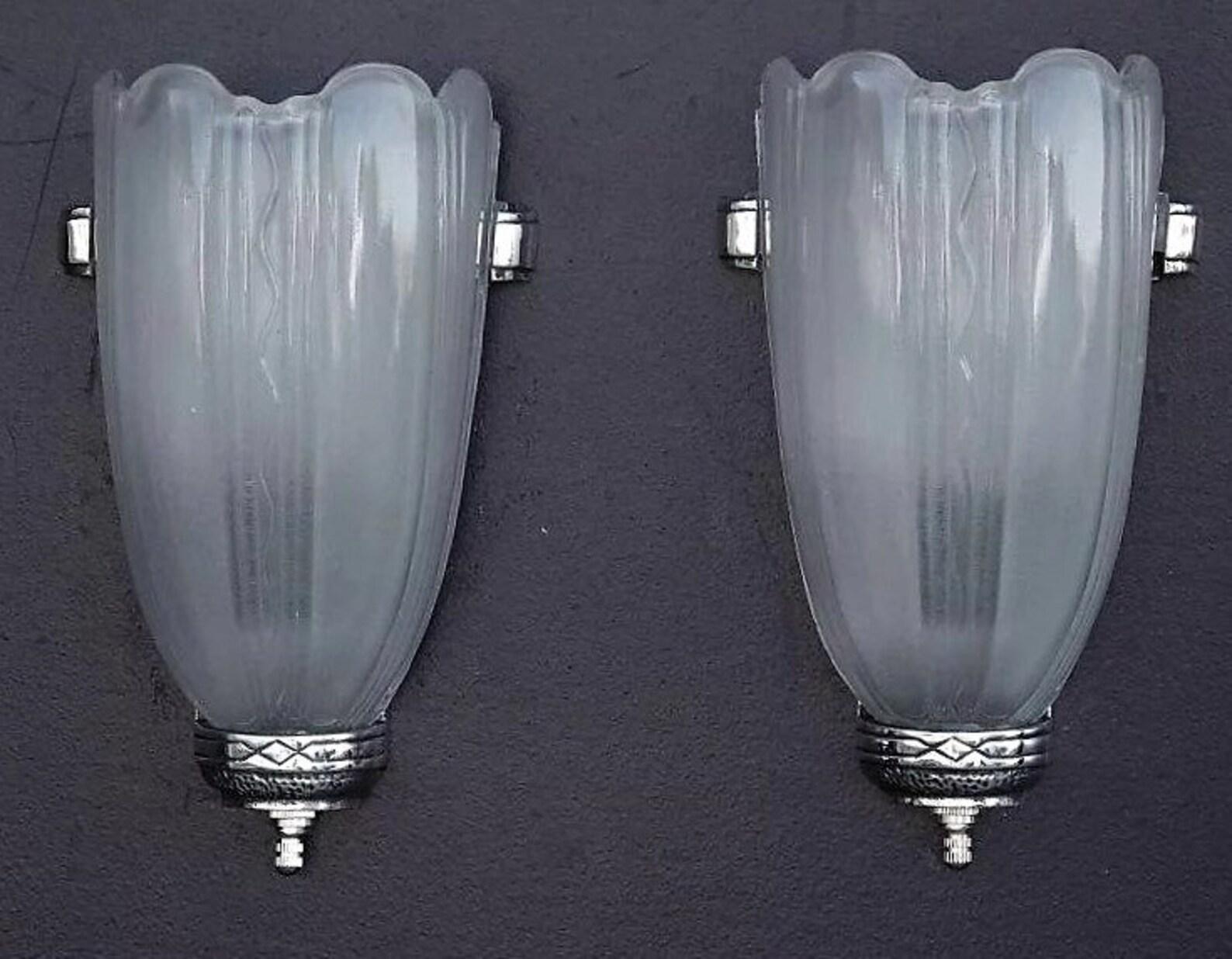 Priced for the pair with two pair available.
Art Deco style sconces. I can see them lighting the lobby in an old Art Deco theater in Miami. Highly polished aluminum backs with subtle yet dynamic Art Deco design. Note the highly reflective glossy