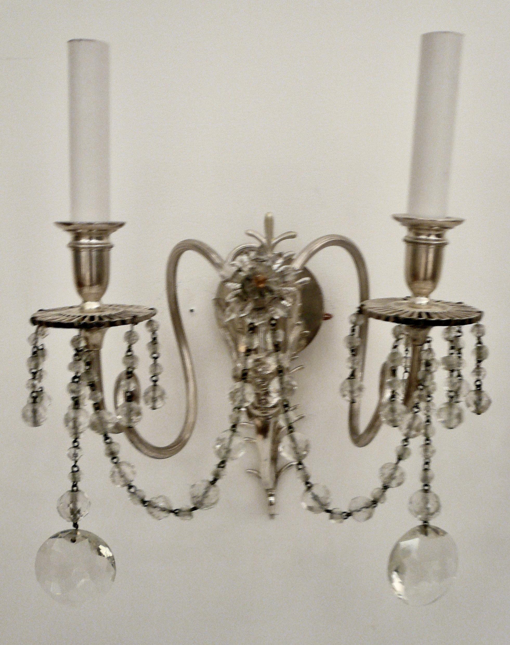 These silver and crystal sconces feature winged busts of putti, and feather form backplates.