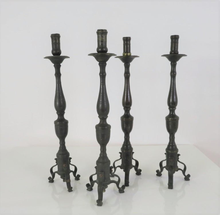 Late Baroque or early Rococo Pair of sinuous form candlesticks. Italian born, they were probably alter pieces and have a subtle decoration on the candleholder top and curlicue legs at the bottom. The tubular centers have intermittent urn and vase