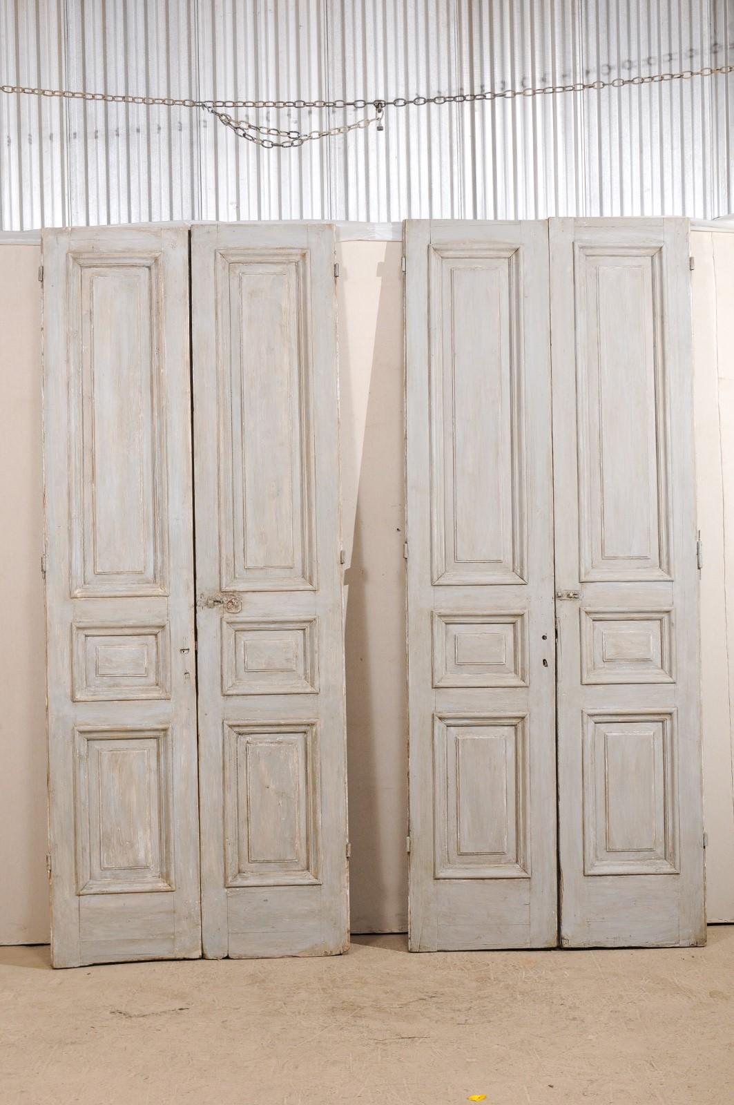 A set of two pairs of 19th century three-paneled French painted wood doors. This exquisite set of two pairs of French doors each feature three carved and raised panels, nicely trimmed, with a smaller panel at centre, between a longer,