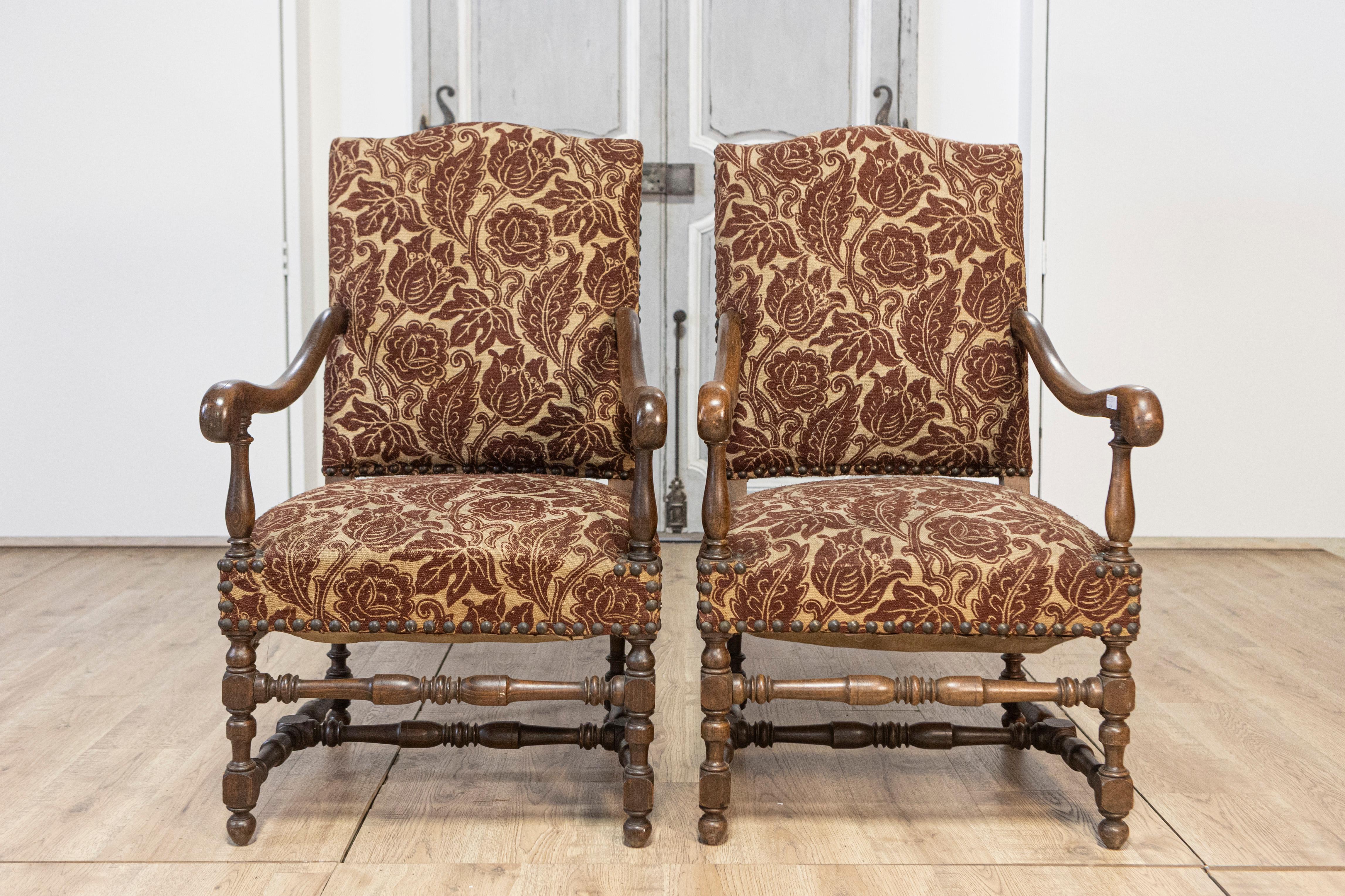 Esta hermosa pareja de sillones franceses del siglo XX rezuma elegancia atemporal y artesanía tradicional. Las sillas tienen marcos de madera bellamente tallados, probablemente de nogal, que muestran su durabilidad y su rica pátina natural. Las