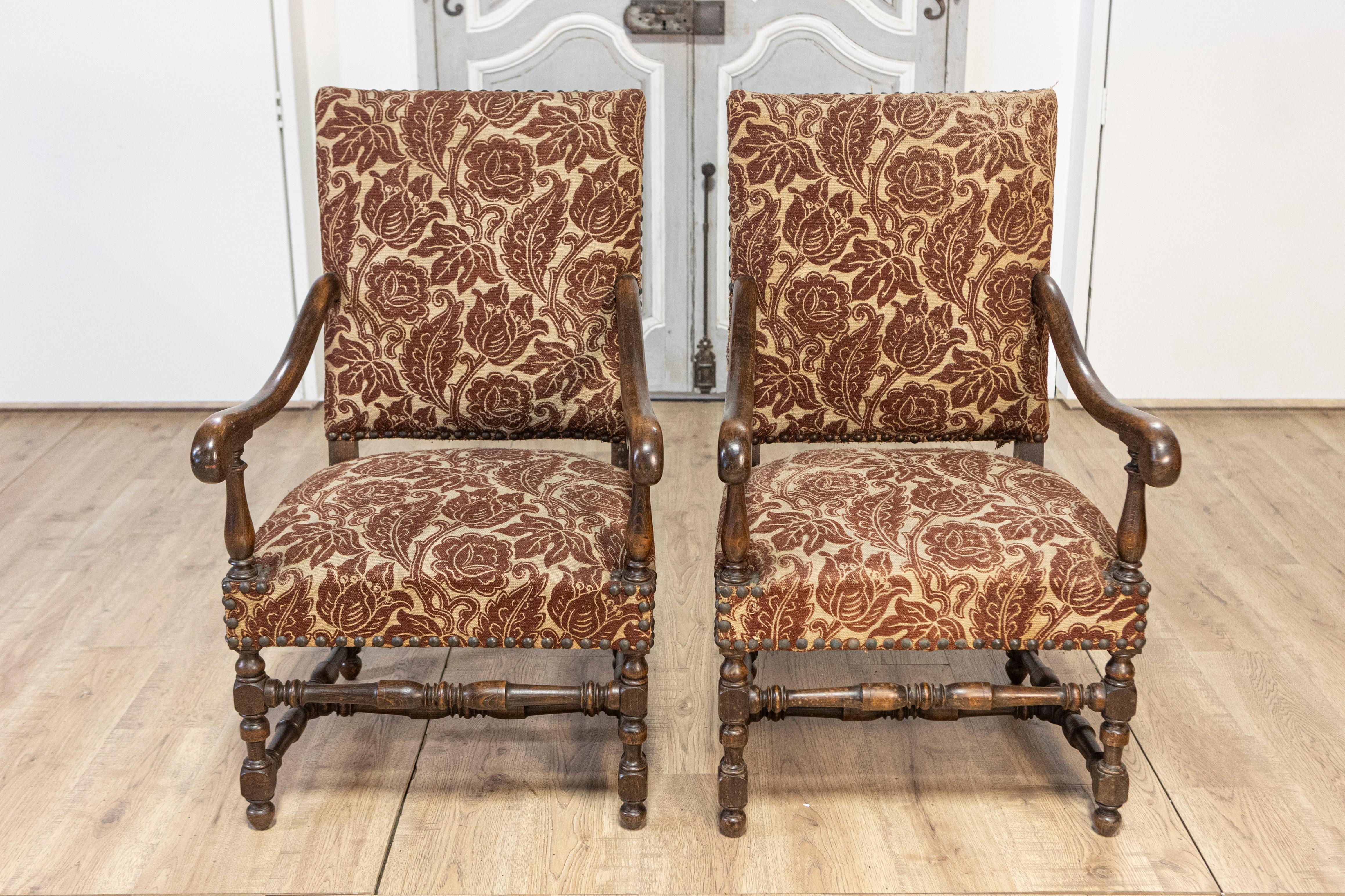 Questa elegante coppia di poltrone francesi del XX secolo è un esempio di design e artigianato senza tempo. Realizzate in noce massiccio, le sedie sono caratterizzate da telai intagliati dallo stile meraviglioso, con braccioli arrotondati e gambe