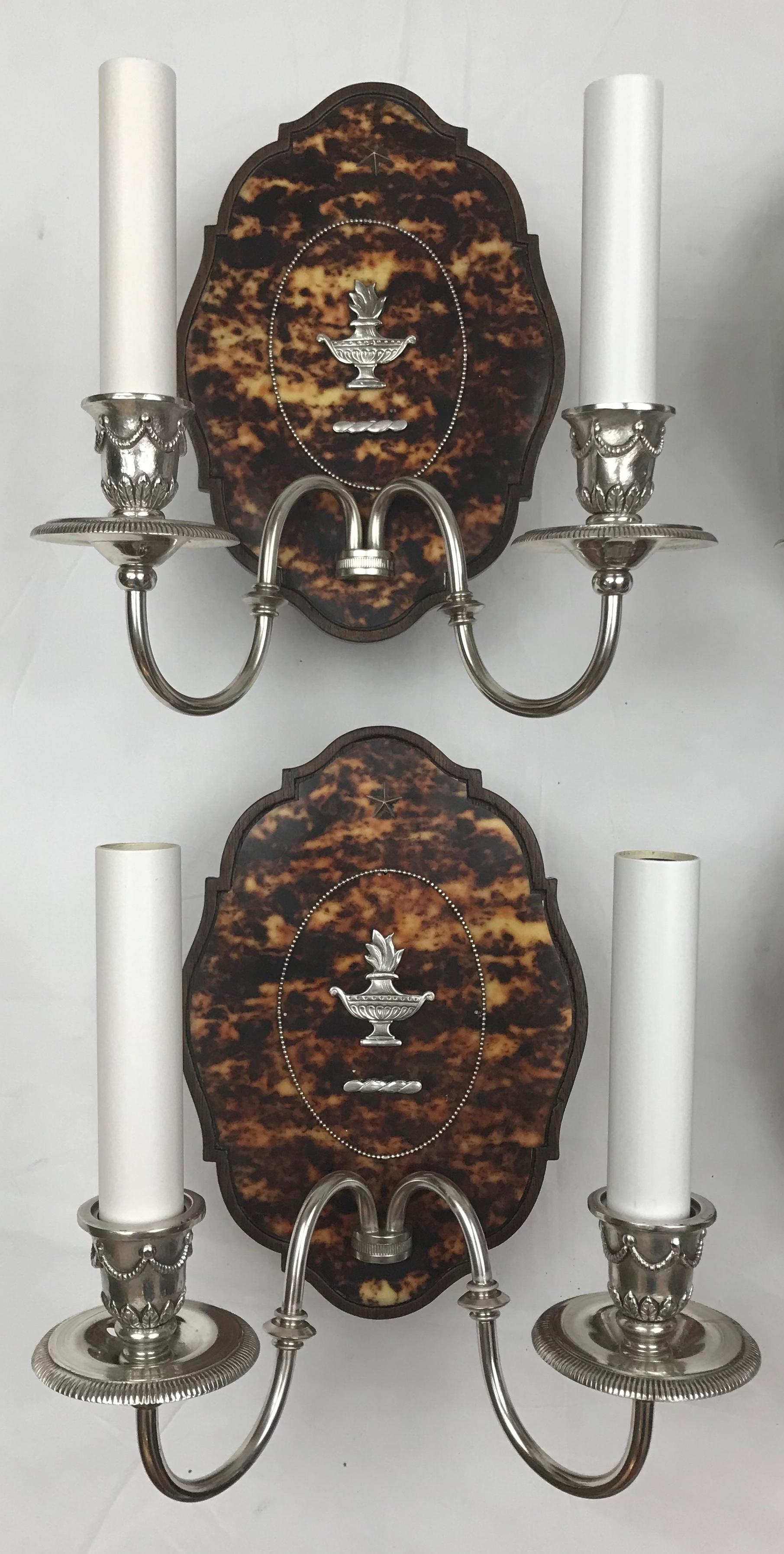These exceptional sconces are by the renown maker Edward F. Caldwell & Co.  The cartouche form carved walnut backplates feature silver mounts on beautifully figured tortoise shell. The sconces are newly rewired, and are ready for use.