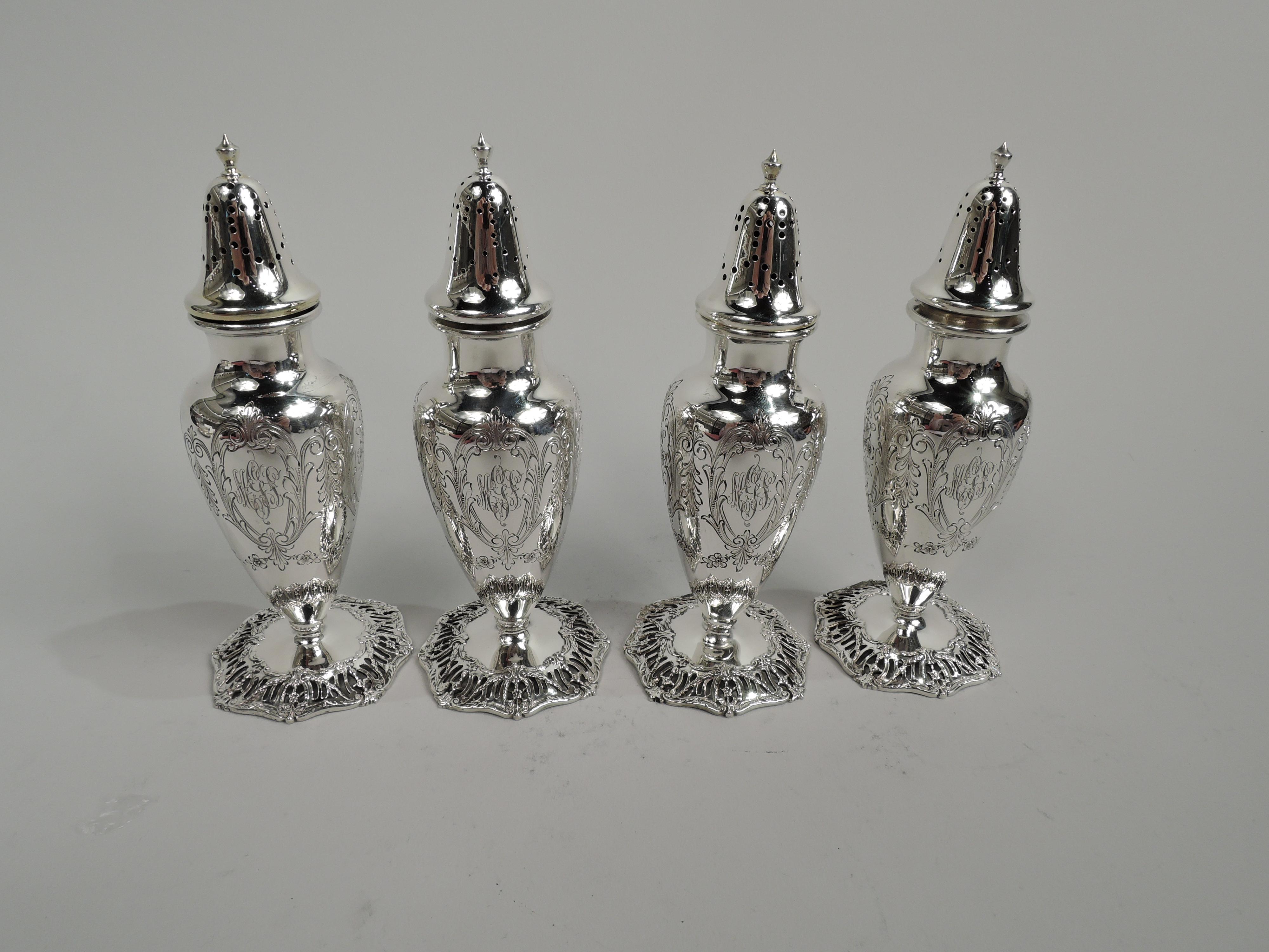 Two pairs of Edwardian Regency sterling silver salt & pepper shakers. Made by Graff, Washbourne & Dunn in New York, ca 1909. Each: Ovoid body with engraved scrolled frames inset with flowers and leaves. One frame engraved with interlaced script
