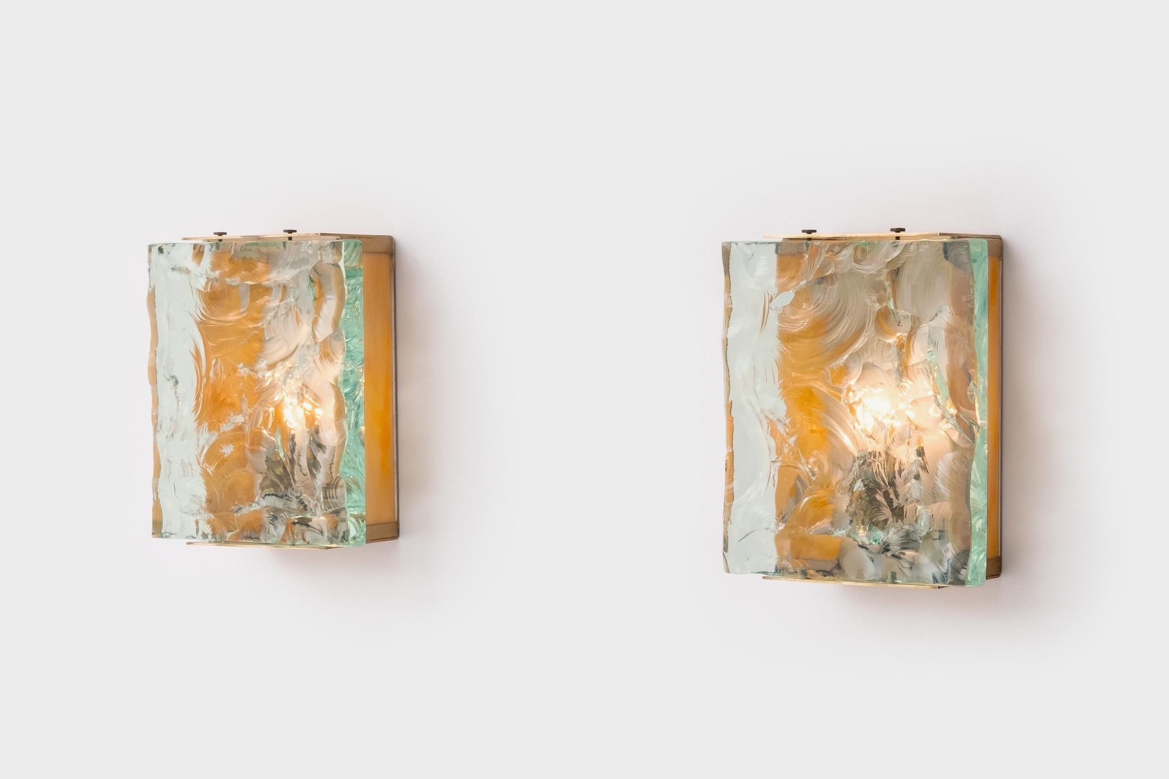 Exceptional wall sconces mod. 2311 by Max Ingrand for Fontana Arte, Italy 1964. Beautiful combination of the brute extraordinary thick hand chiseled glass with the refined brass framing and marbled yellow glass strokes. The lamps provide a nice and