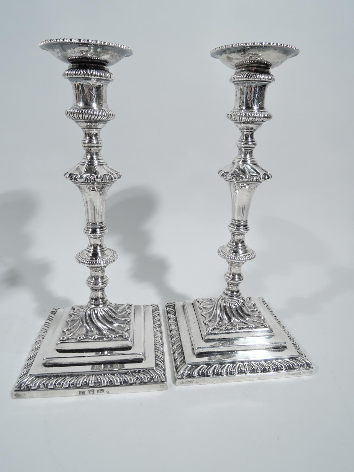 Two pairs of English Georgian sterling silver candlesticks, 1760. Each: Knopped spool shaft on twisted-fluting base mounted to stepped square base. Spool socket with beaded and detachable bobeche. Gadrooning. Engraved armorial and interlaced script