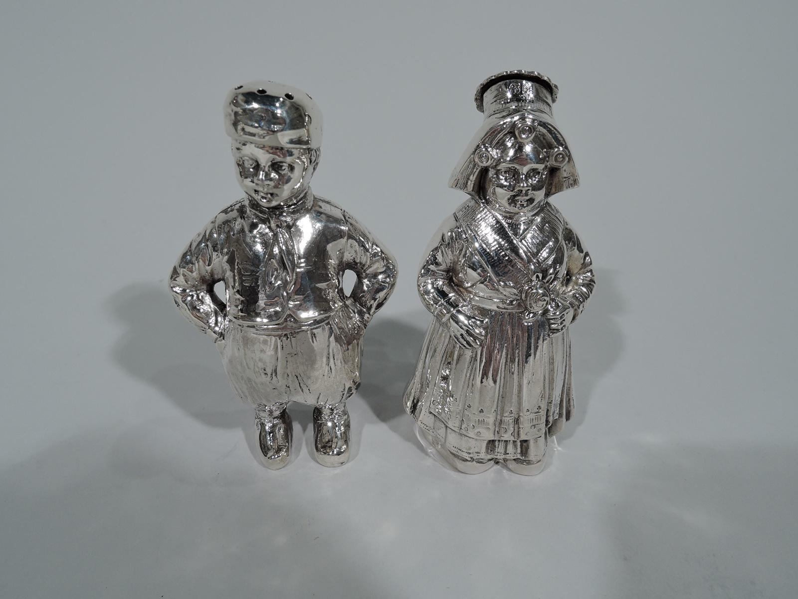 Two pairs of German 800 silver figural salt and pepper shakers. Each pair comprises one boy and one girl. The boys wear baggy trousers and strike a defiant pose with hands on hips. The girls, with shawls and aprons layered over their gowns, appear