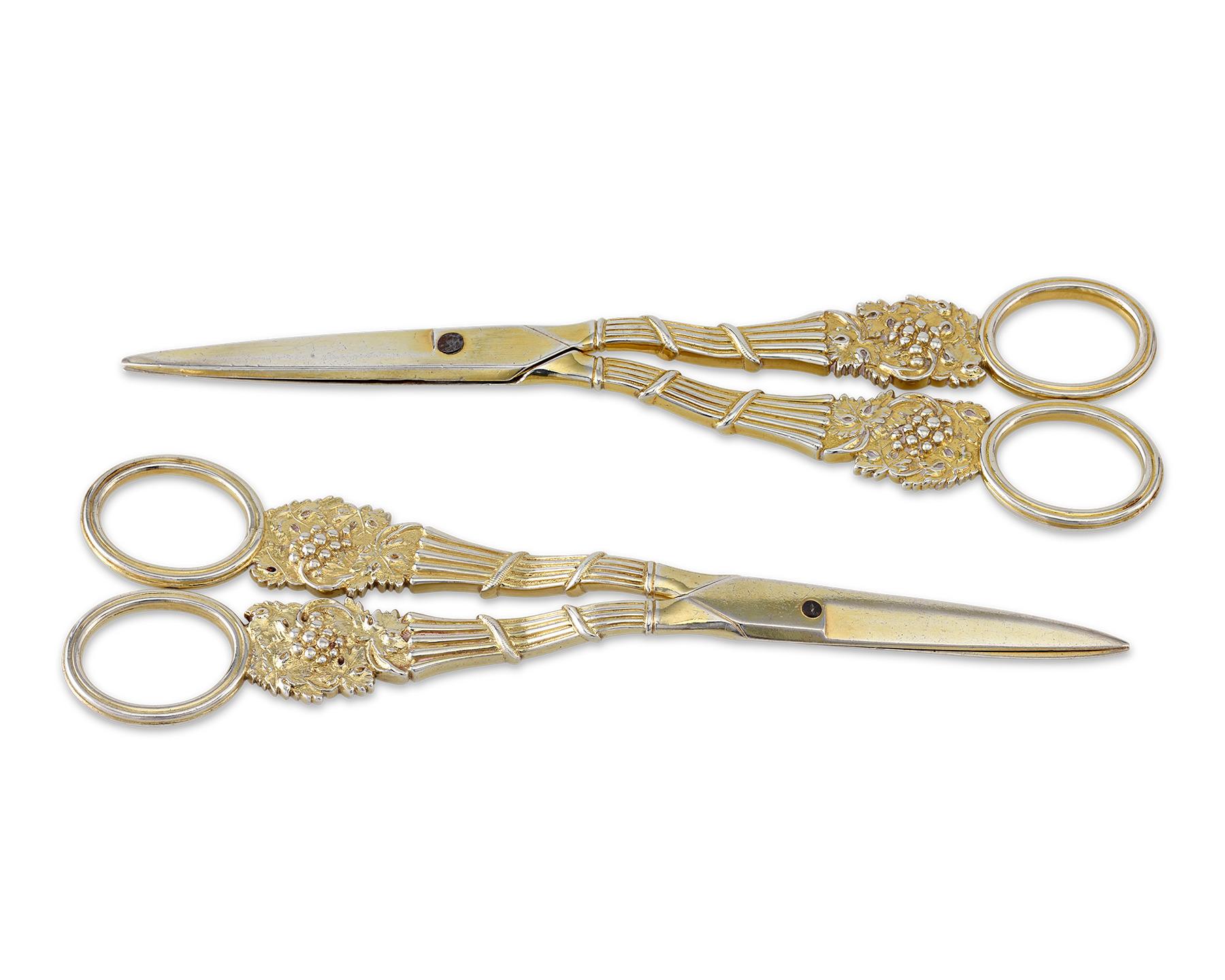 Comprised of silver-gilt, these two pairs of beautifully crafted grape shears were designed and manufactured in by famed London silversmiths William Eley and William Fearn. The pairs’ handles are cast elegantly with Bacchanal motifs of fruiting