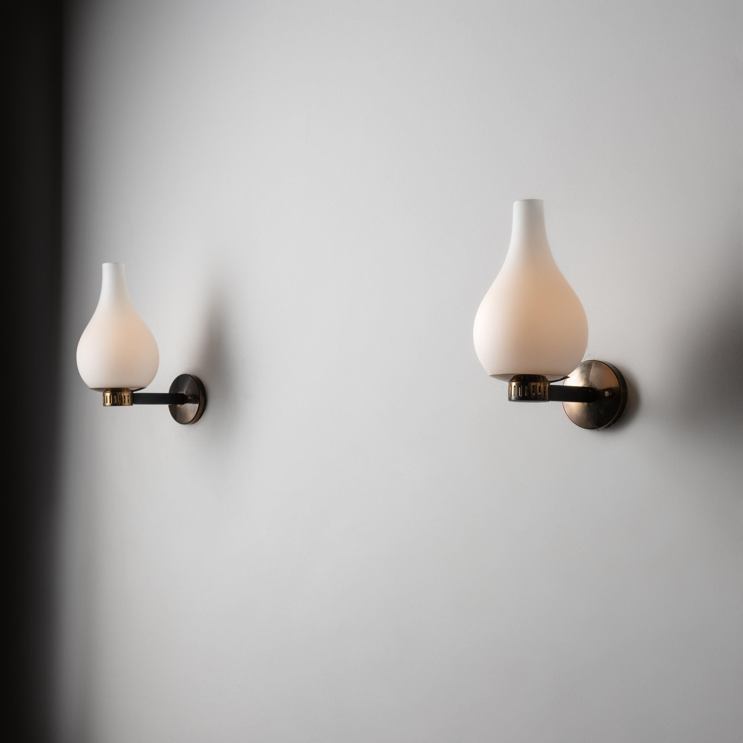 Pair of Sconces by Stilnovo. Designed and manufactured in Italy, circa 1950's. Brushed satin glass diffusers, brass. Custom brass backplates. Rewired for U.S. standards. We recommend one E27 60w maximum bulb per fixture. Bulbs not included. One pair