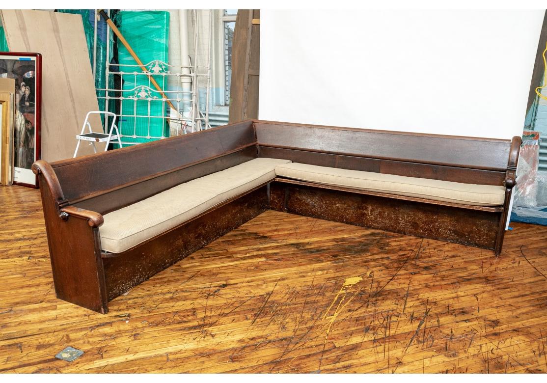 A large Pair of custom-fitted Corner Benches from an old Congregation. The Pair are end-cut to fit into each other and forming a Corner Unit. In a good deep stain and retains their original Metal Number Plates, Back Book Racks and Attached Metal