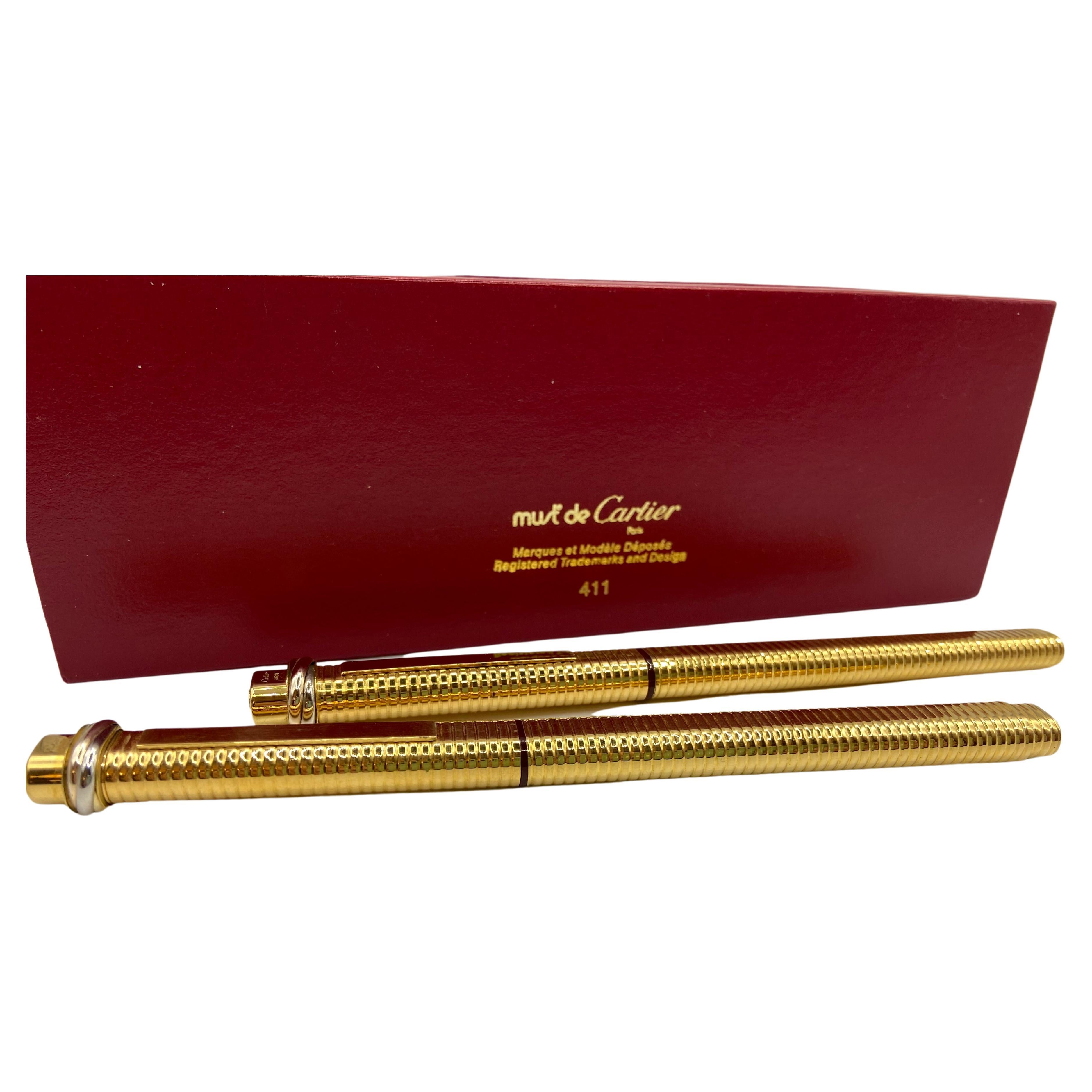 Two pens, a fountain pen and a roller, Santos model by Cartier, 18 kt gold plated.
Never used, small signs of aging. One box.The decorative band with interweaving is in white, yellow and rose gold.
It has a pocket clip which is lifted by pressing