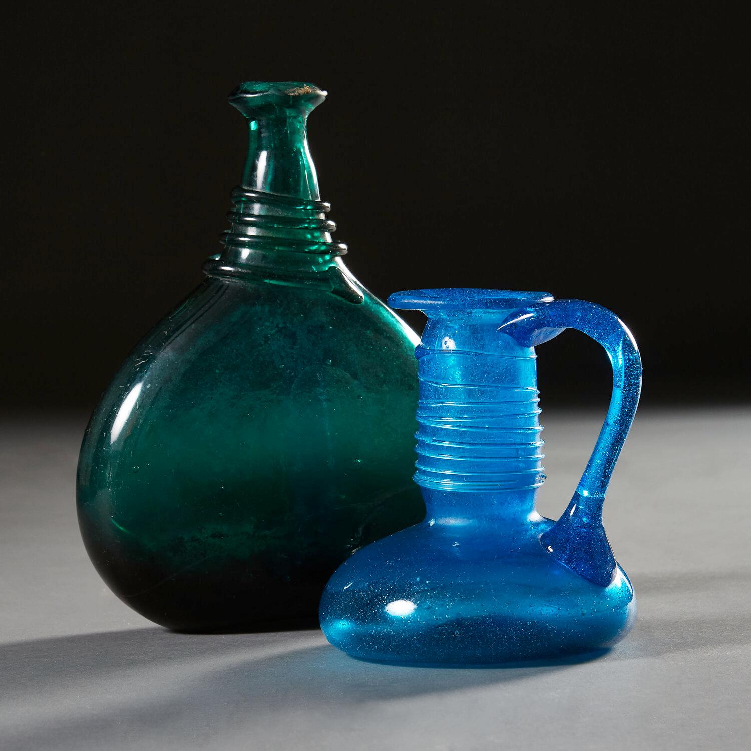 Two late eighteenth century Persian glass vessels, the green bottle with serpent coil decoration to the neck, the blue pitcher also with serpent coil decoration to the neck, with loop handle and flared rim. 

Please note that the measurements