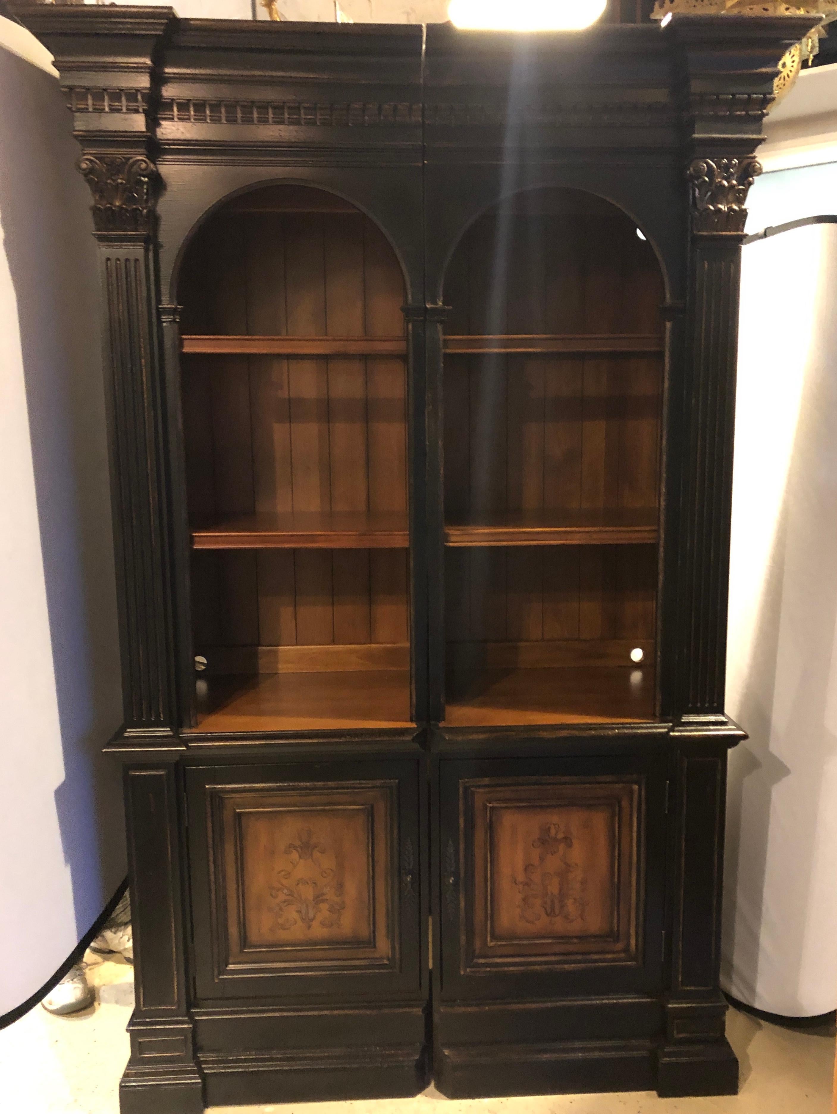 A two-piece bookcase cabinet paint decorated by Hooker Furniture Company. This custom quality bookcase or showcase cabinet has a lighted cabinet top with open shelved area above double door storage compartments. The whole in a nice ebony finish that
