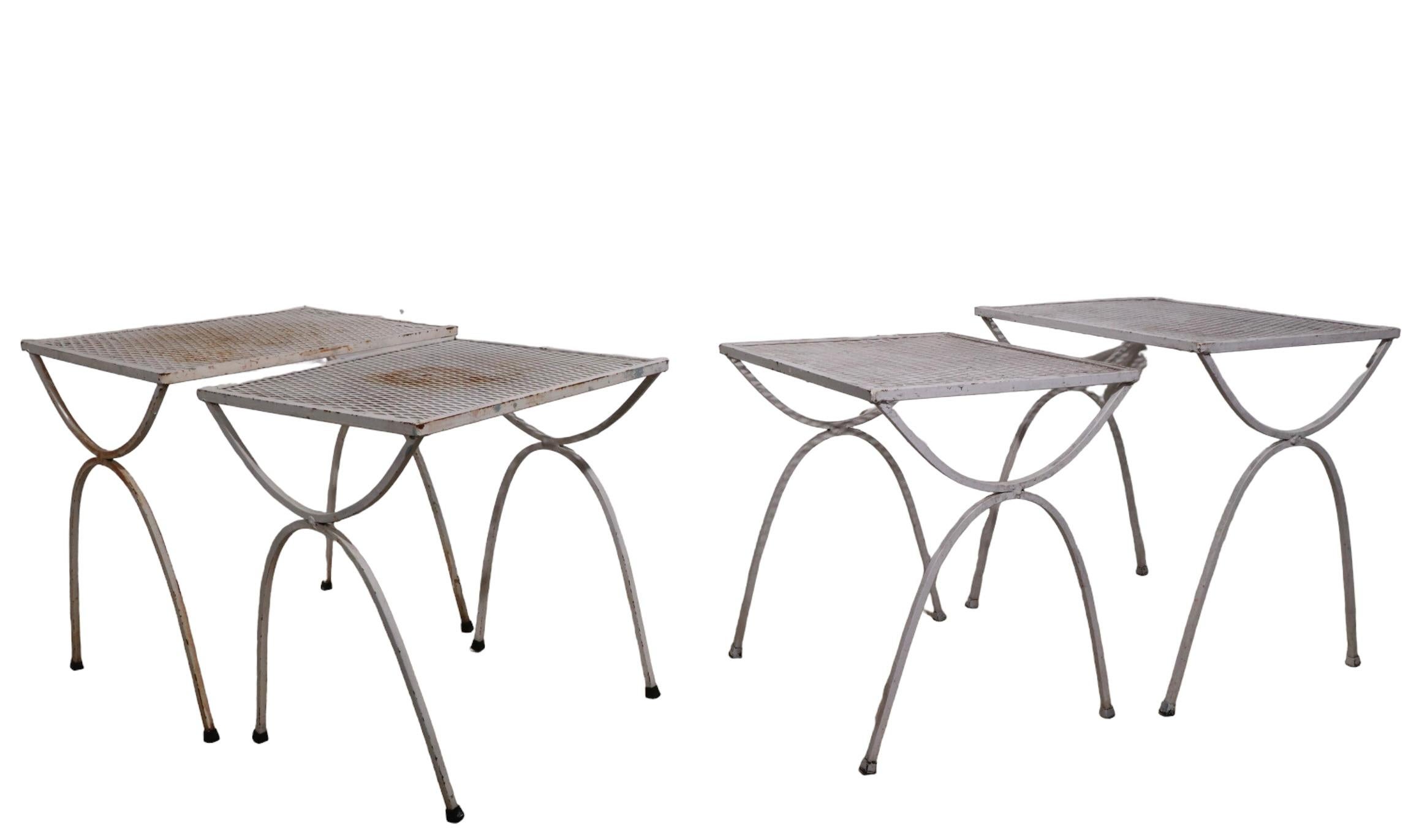 Chic architectural set of two nesting tables by Salterini. Constructed of wrought iron, and metal mesh, these tables are suitable for both indoor and outdoor use, they are structurally sound and sturdy, all show some cosmetic wear to the paint