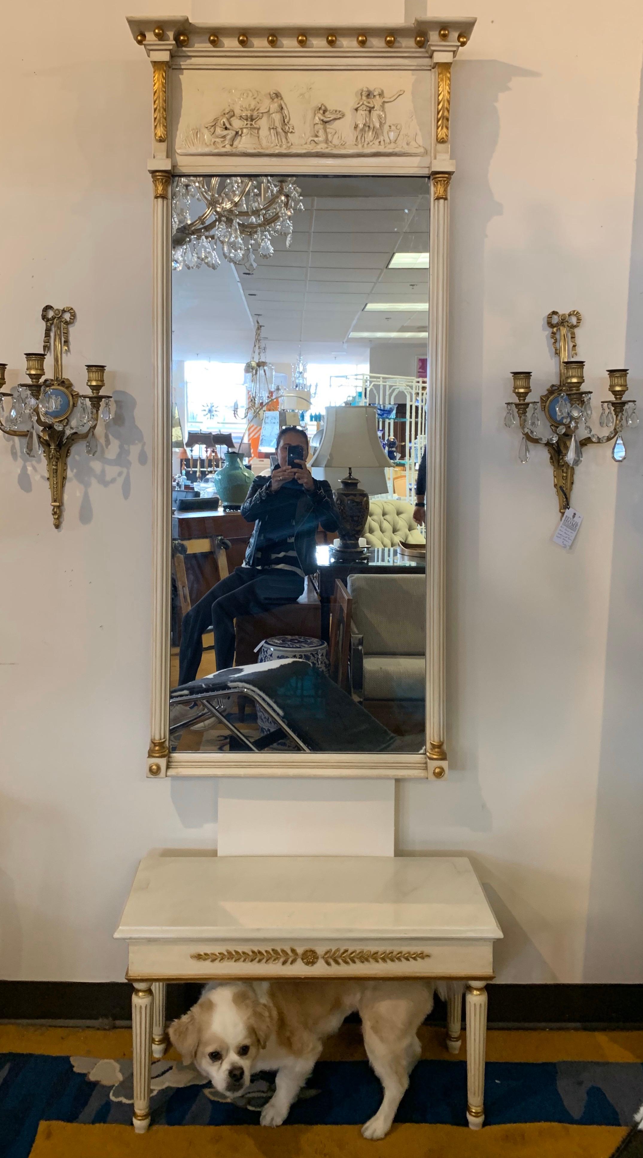 Exquisite cream and gold gilt neoclassical style pier mirror with matching table with marble top. Has raised carved relief. At top and on console below. An iconic Decorative Arts masterwork. The dimensions of the mirror are below and the console