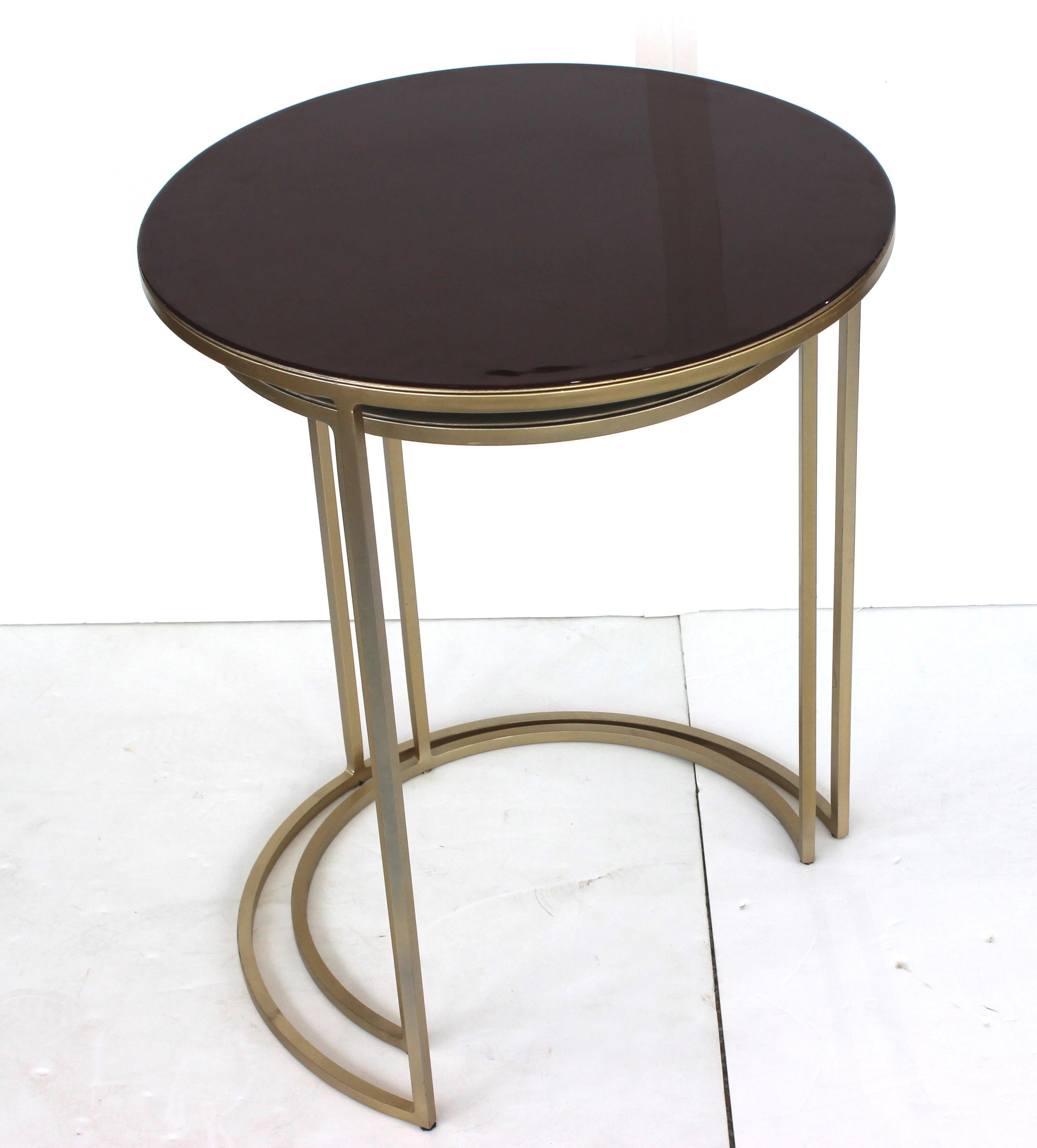 This stylish and chic two-piece nesting tables date the 1990s and are very much in the manner of streamlined pieces created during the Art Deco period.  They both have a gold/bronze toned finish on the frames, and the lacquered tops have a deep