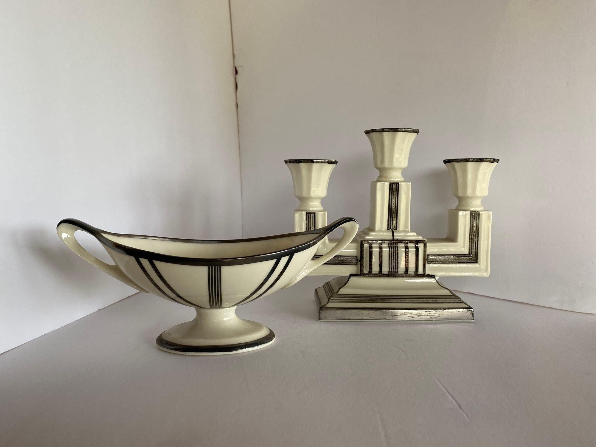 Stepped Art Deco ceramic candelabra and matching sugar bowl with sterling silver overlay by Lenox.

Candle opera: height: 6.5 in. width: 7.5 in. depth: 3 in.
Sugar bowl: height: 3.5 in. width: 8.5 in. depth: 3.5 in.

Circa 1930.