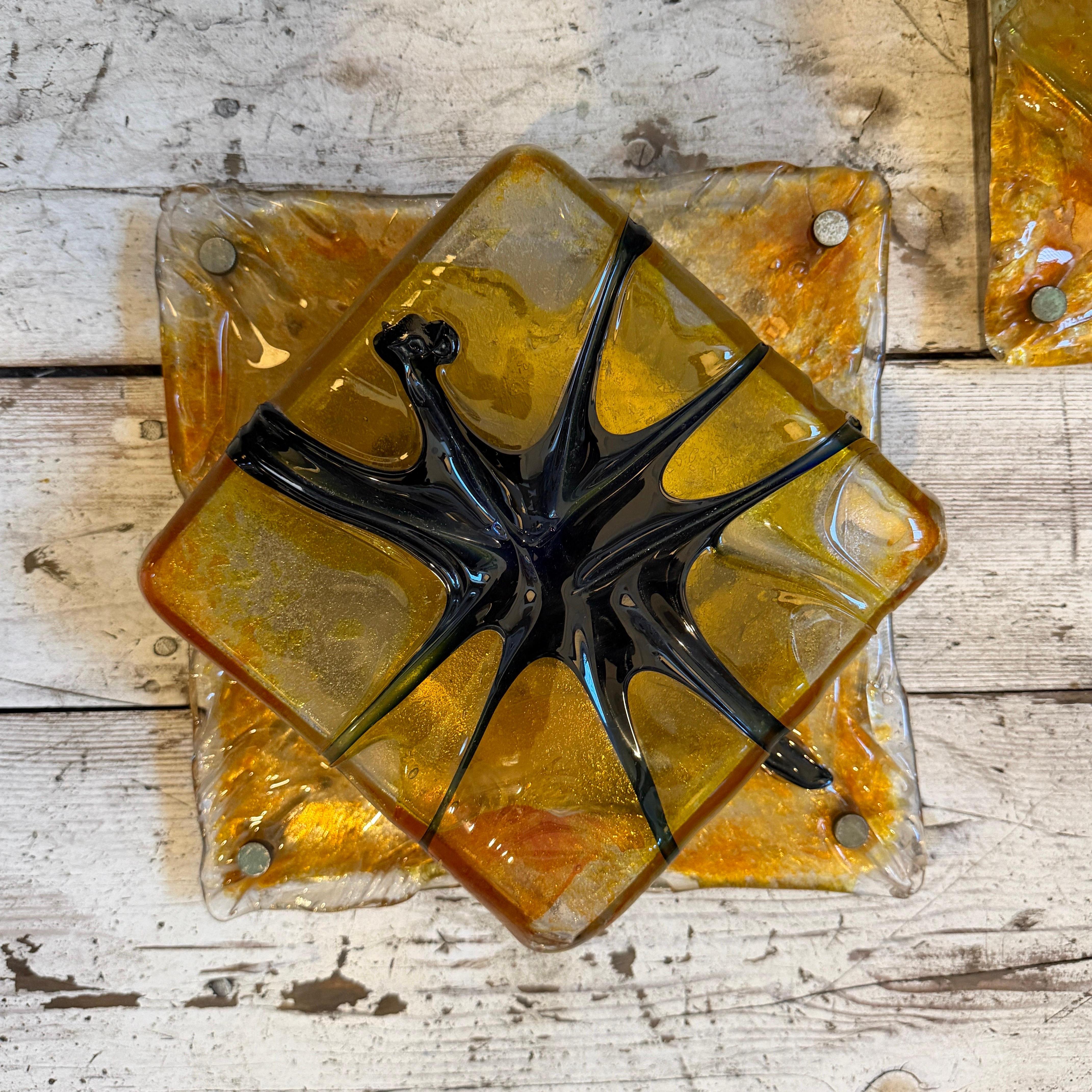 These exquisite and rare Italian light fixtures are a stunning example of 1970s Space Age design, attributed to the renowned Mazzega Murano glassworks. This is a pair of square wall sconces or ceiling lights, each crafted from thick, richly textured