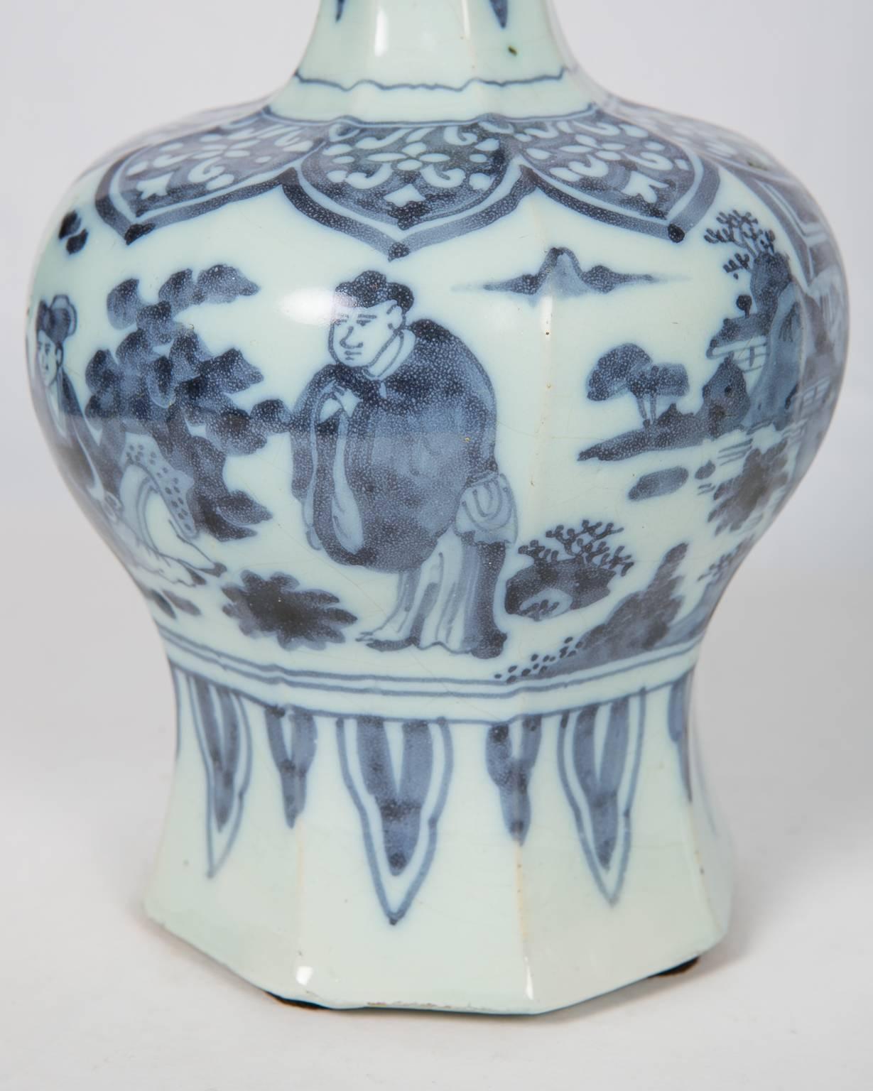 We are pleased to offer this matched pair of blue and white delft vases dates to the late 17th century. Each vase is decorated with figures and floral patterns. They share the same style of composition. Each long neck is painted with a flower branch