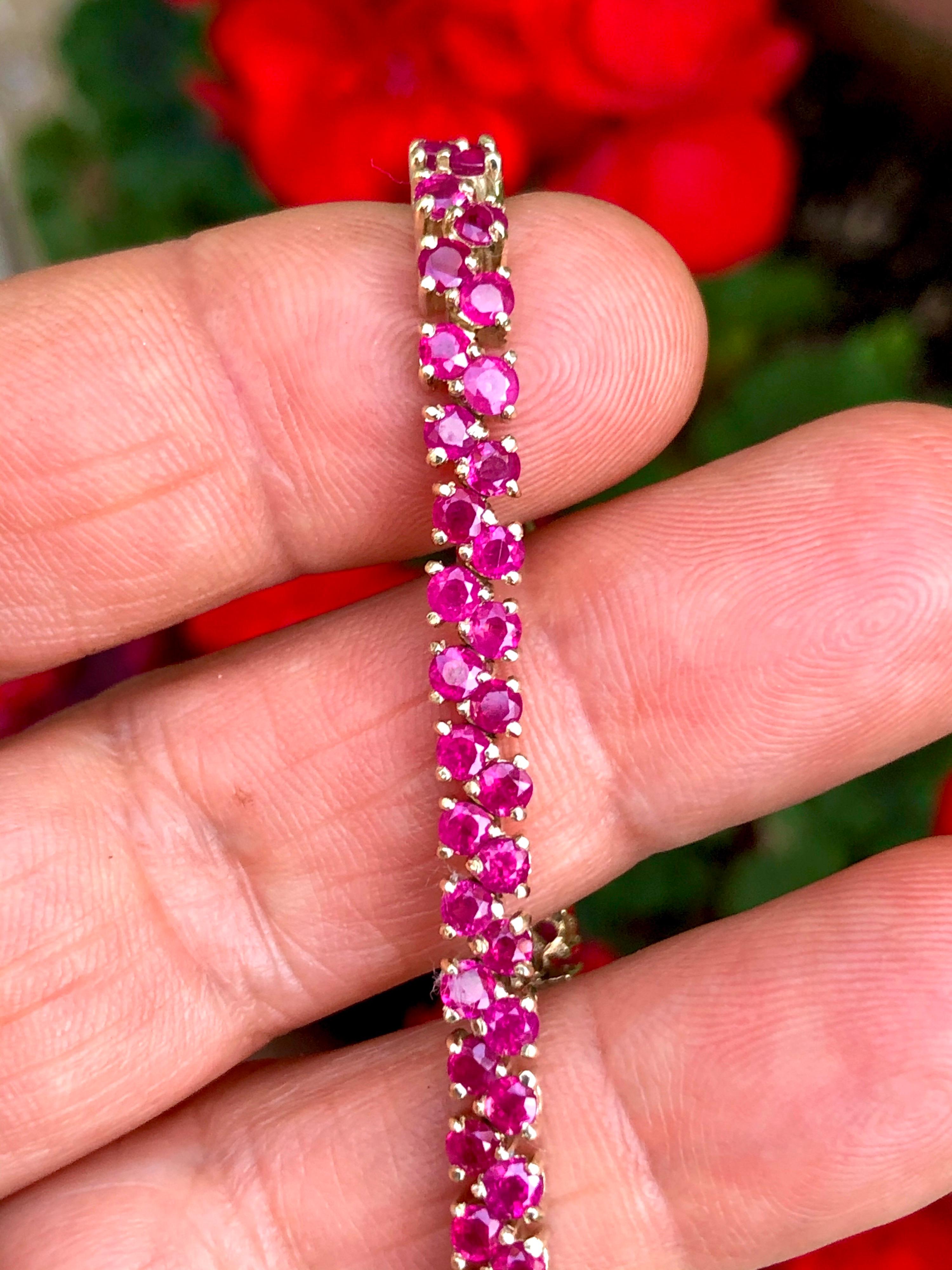 A vibrant and Flexible band designed as a two-row of rubies,  14k yellow gold. The bracelet holds 94 round cut rubies. The rubies have a total weight of approximately 11.00 carats, with a pinkish-red hue throughout. The bracelet measures 7 inches in