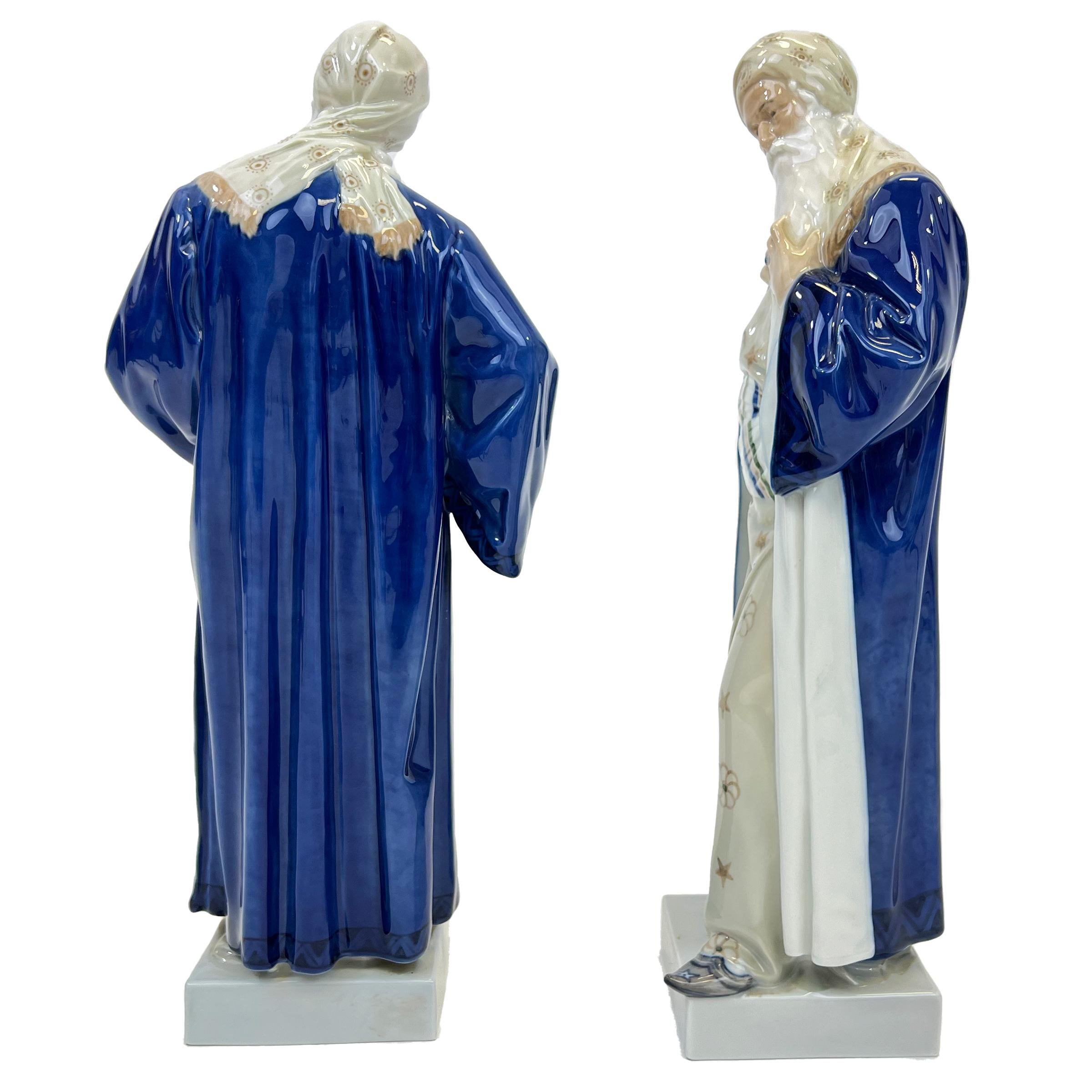 Two large porcelain figurine of Nathan the Wise originally designed by Adolf Ferdinand Walter Jahn. Long bearded man standing on a square base wearing blue robe, and matching long dress with head scarf, Stamped at the base.