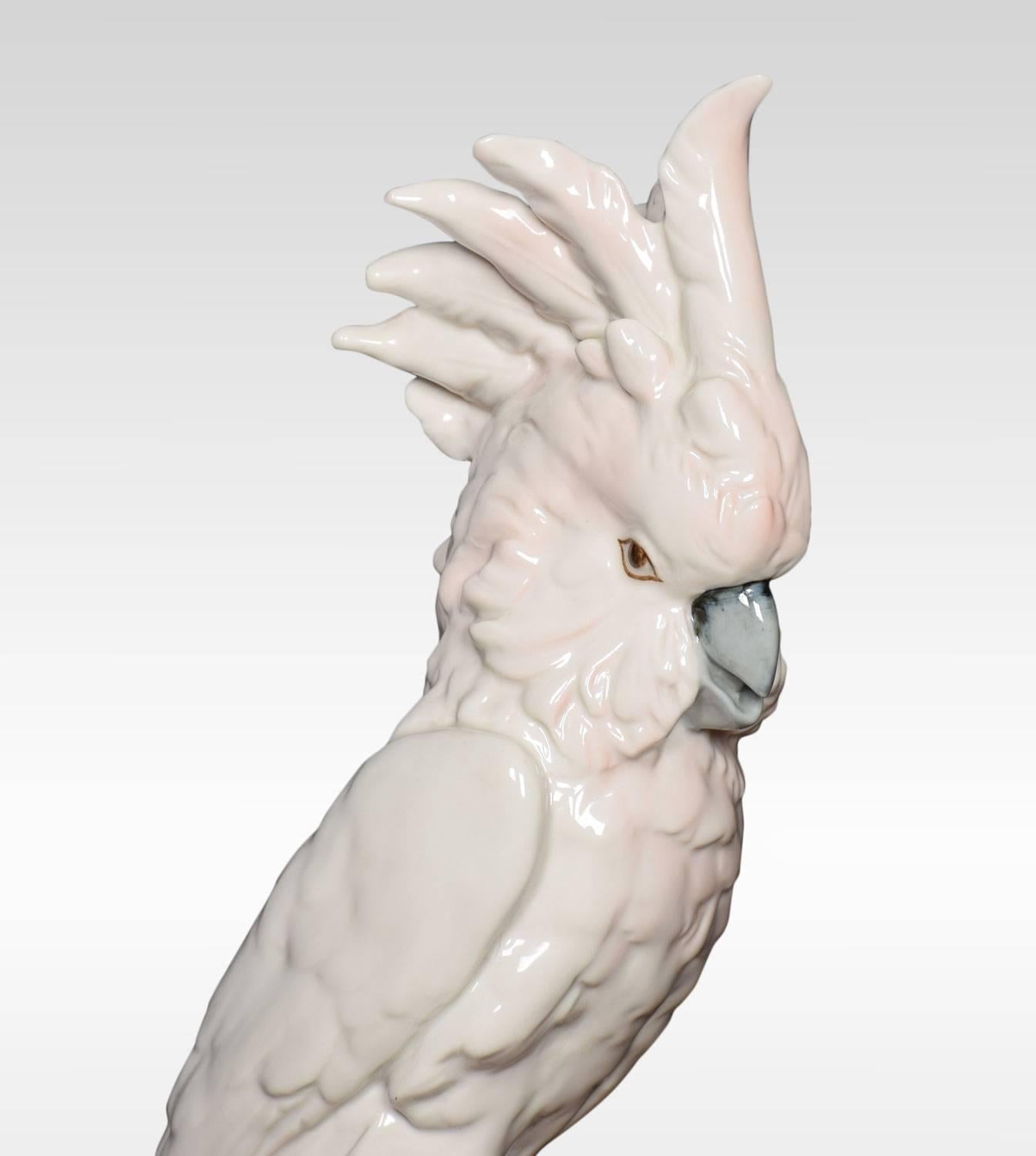 A mid-20th century Royal Dux porcelain figure of a cockatoo. The cockatoo is displaying it’s crest and is sitting on a branch with flowers underneath. Together with another much smaller cockatoo sitting on a branch. Bottoms marked with all the