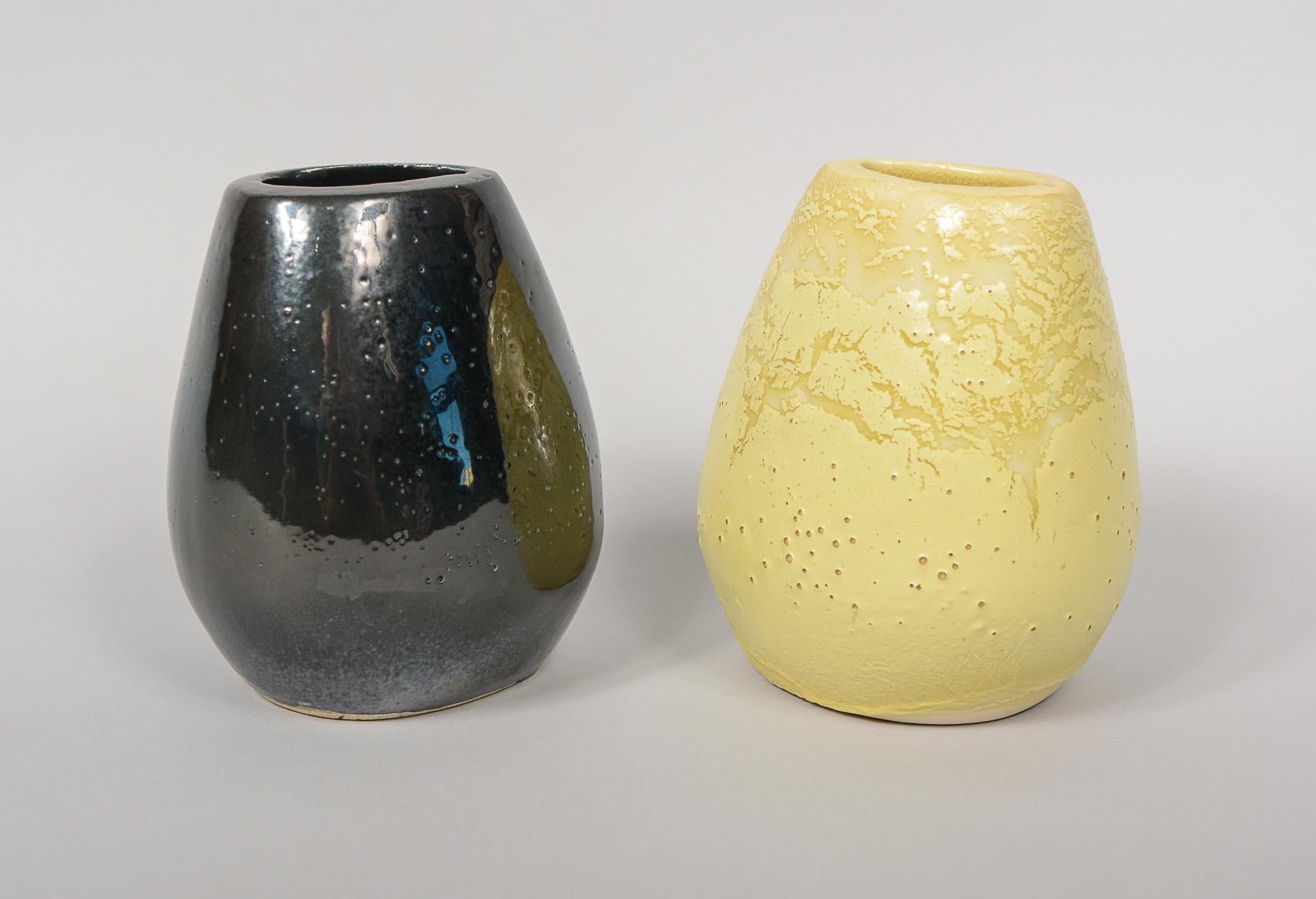 Two corsage vases designed by Russel Wright for Bauer. This short lived line was only produced 1945 - 46. These are in jonquil yellow and gun metal. The gun metal vase has some small scratches.