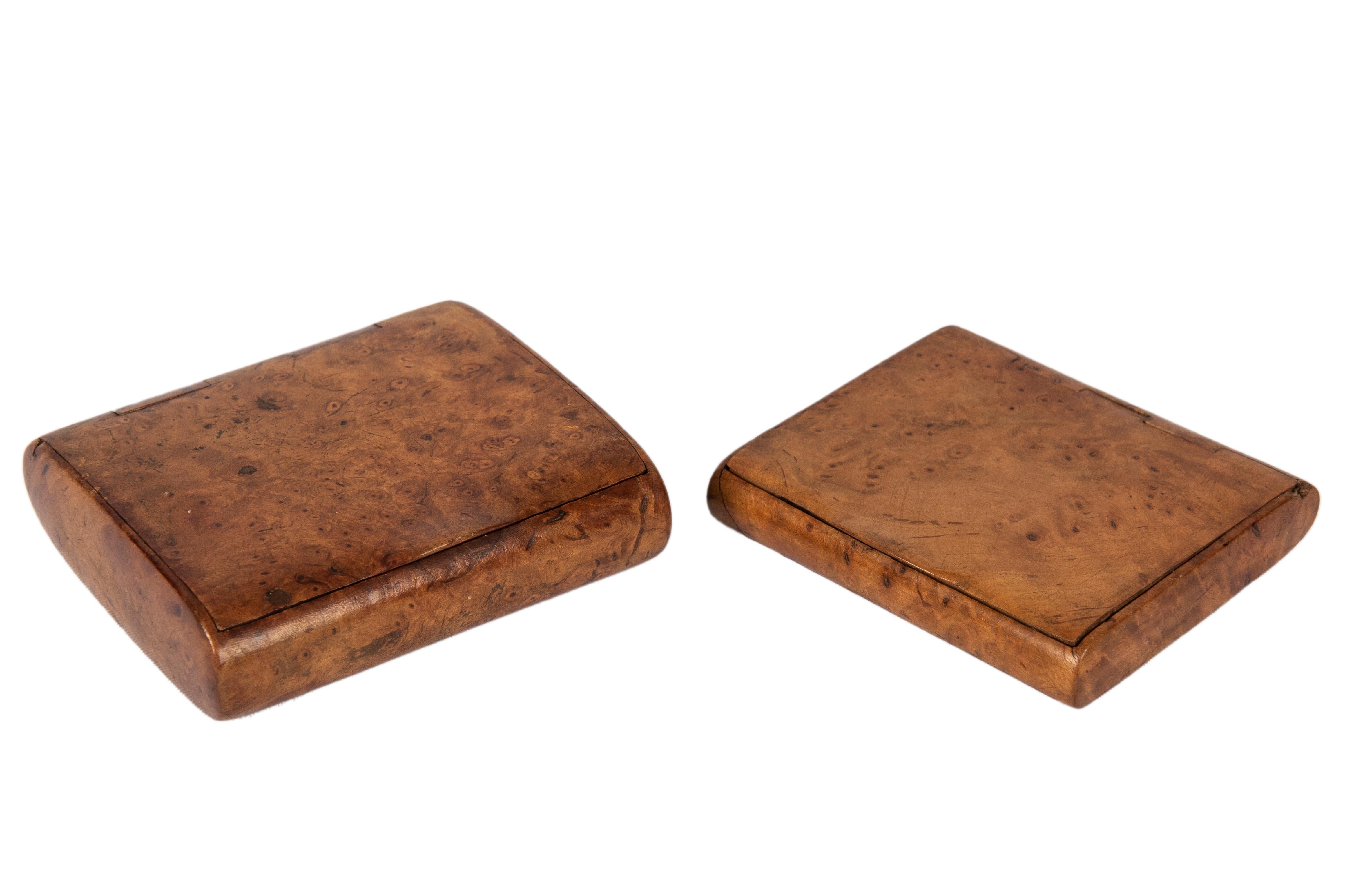 Birchwood Russian cigarette cases, his and hers from the Romanov era, each of burled wood and oval section, hinged with thumbpiece, lightweight mementos of the tsarist era, easy to carry or slip in pocket and purse. 

3 ¼ x 3 5/8 x ¾ in. (8.3 x 9.2