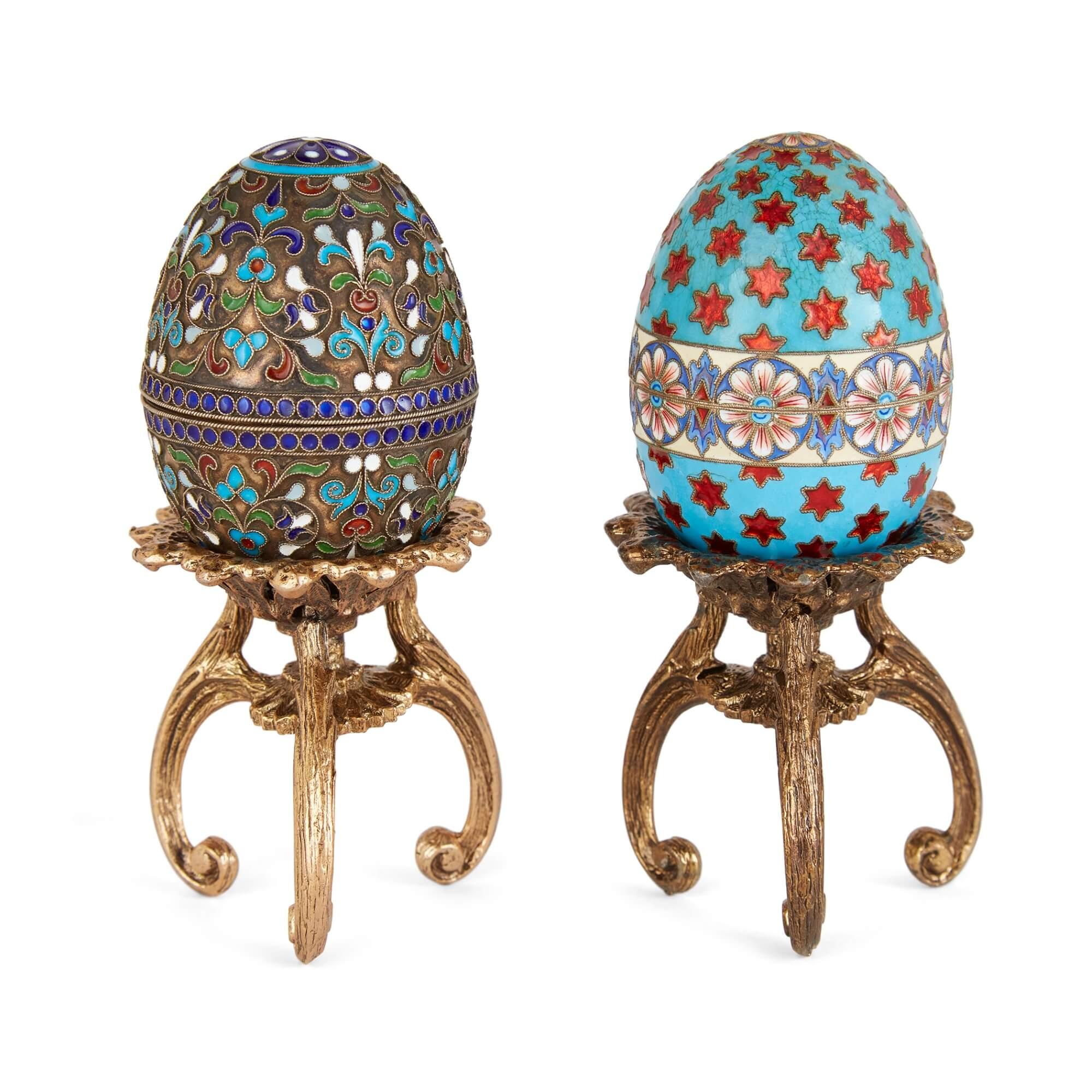 Zwei russische Eier aus vergoldetem Silber und Cloisonné-Email auf Ständern  
Russisch, 20. Jahrhundert 
Höhe 12 cm, Durchmesser 4,5 cm    

Diese prächtigen russischen Eier sind aus vergoldetem Silber gefertigt und mit der komplexen Technik der