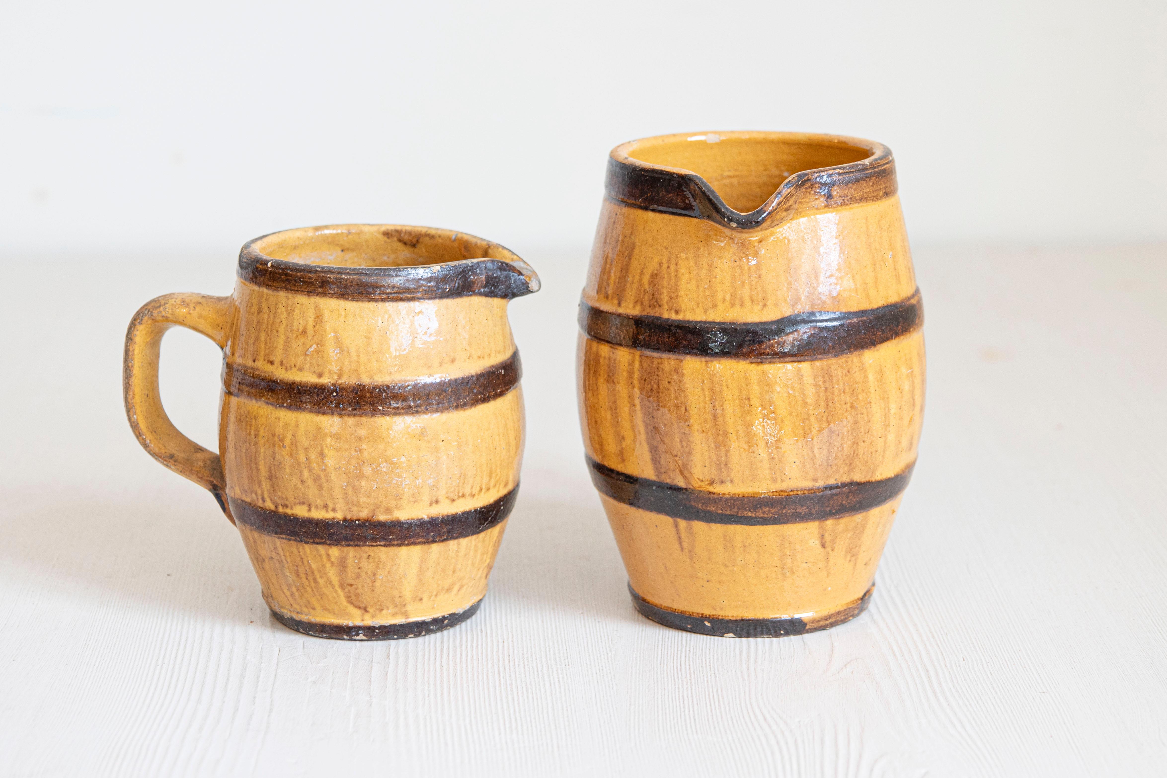 Deux pichets rustiques en poterie française du 19e siècle, avec glaçure jaune, accents bruns et poignées arrière. Elles sont vendues individuellement au prix de 250 dollars chacune. Créées en France au cours du XIXe siècle, chacune de ces cruches