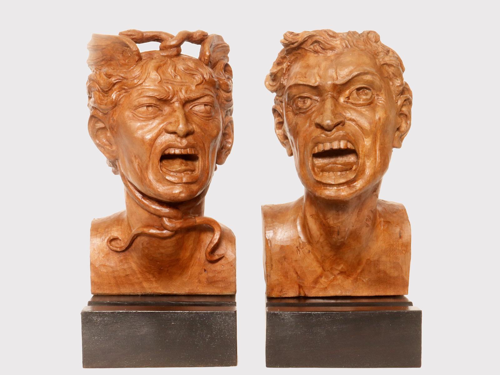Two wooden sculptures depicting the head of Medusa and the head of a man who is petrified by her gaze. Above a rectangular base in ebonized pine wood. The two faces, finely carved, show the Medusa with wings and two twisted snakes. The other, the