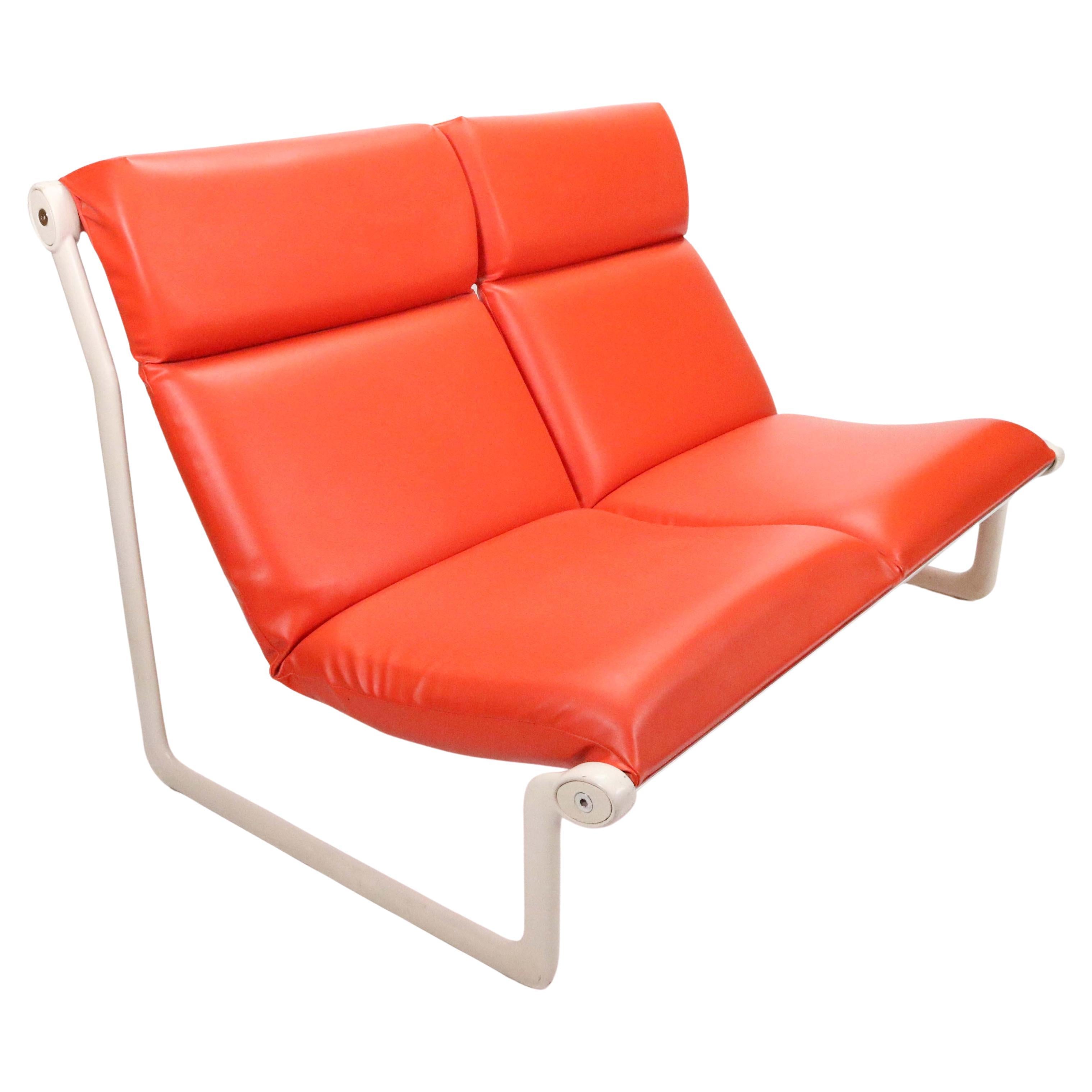 Two-seat sling sofa by Bruce Hannah and Andrew Morrison for Knoll in vibrant 1970s red orange faux leather.

The steel frame has been freshly powder-coated in July 2022 and bears no scratches or blemishes. 

This is truly a beautiful and very