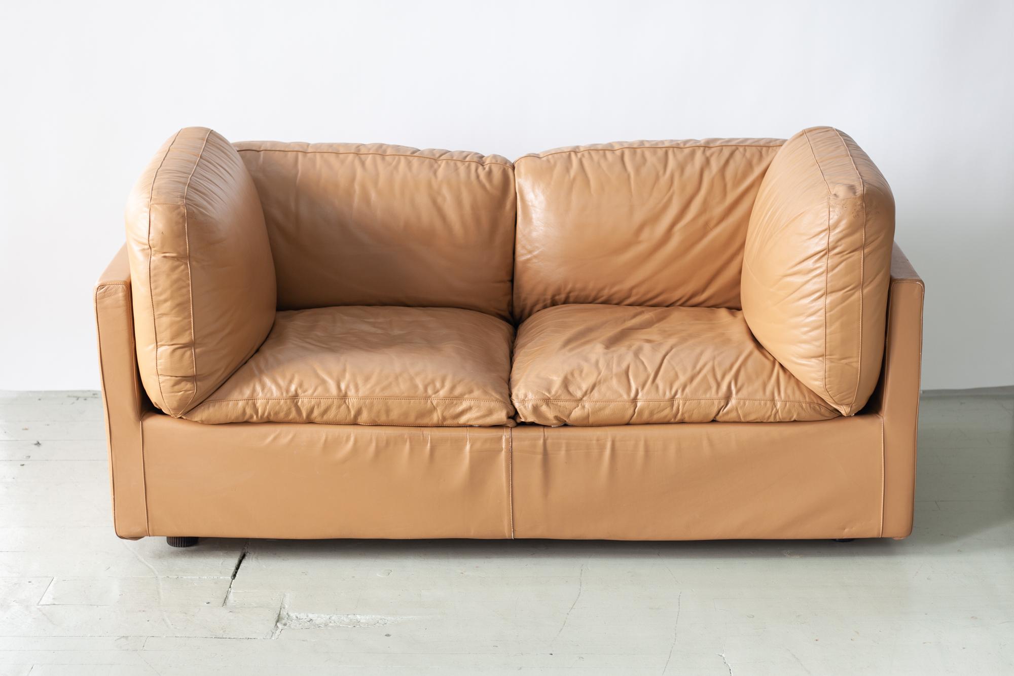 This two seat sofa/ loveseat by Jonathan De Pas, Donato D'Urbino and Paolo Lomazzi for Zanotta is a beautiful, rare piece featuring original leather upholstery made in Italy circa the 1970s. The plush seat cushions are removable and make this piece