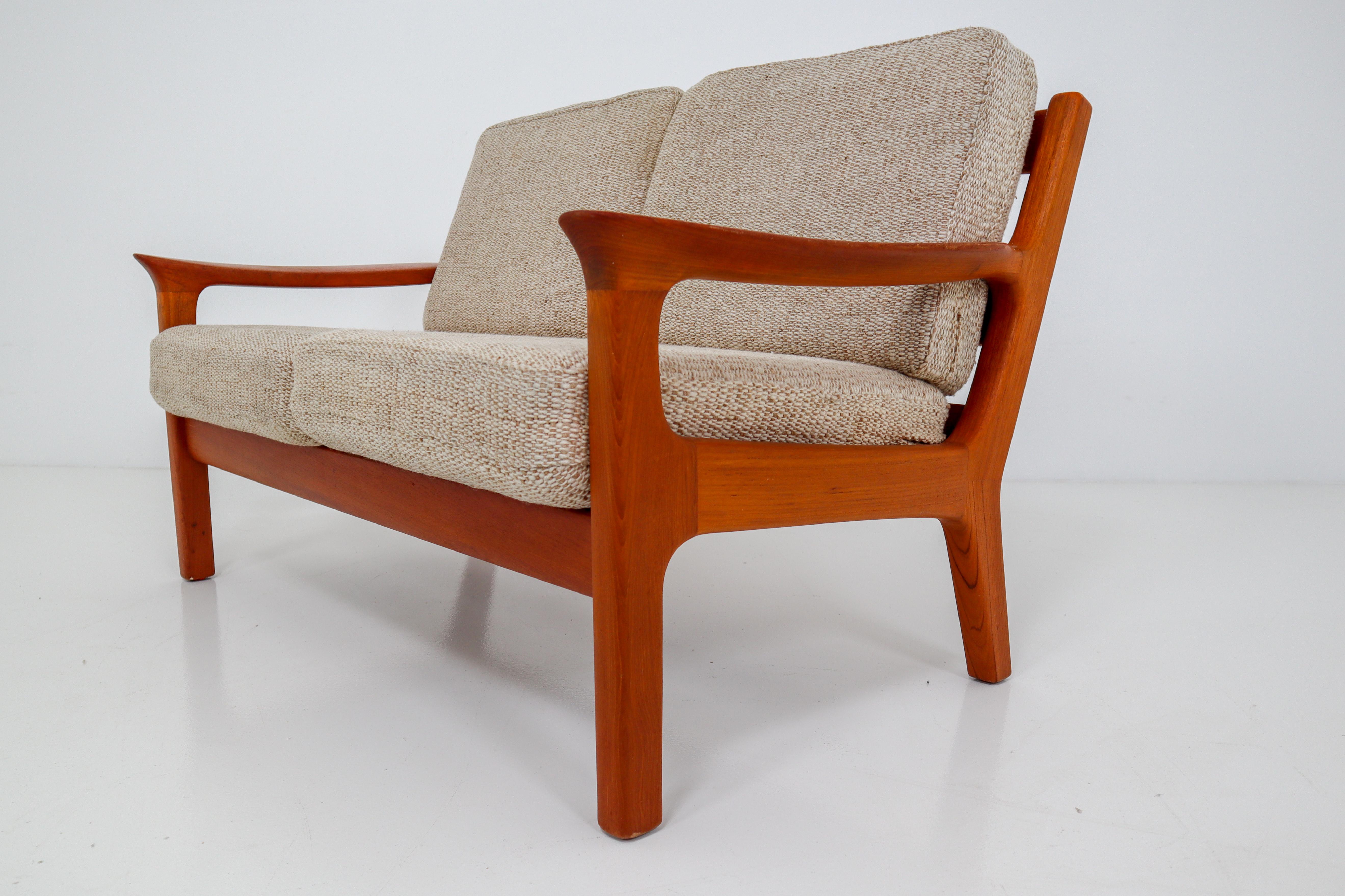 Two-seat sofa in solid teak and cushions designed by the Danish designer Juul Kristensen and manufactured by Glostrup Furniture Factory in the 1960s. The cushions are upholstered with a sandy colored high quality original fabric. The teak wooden