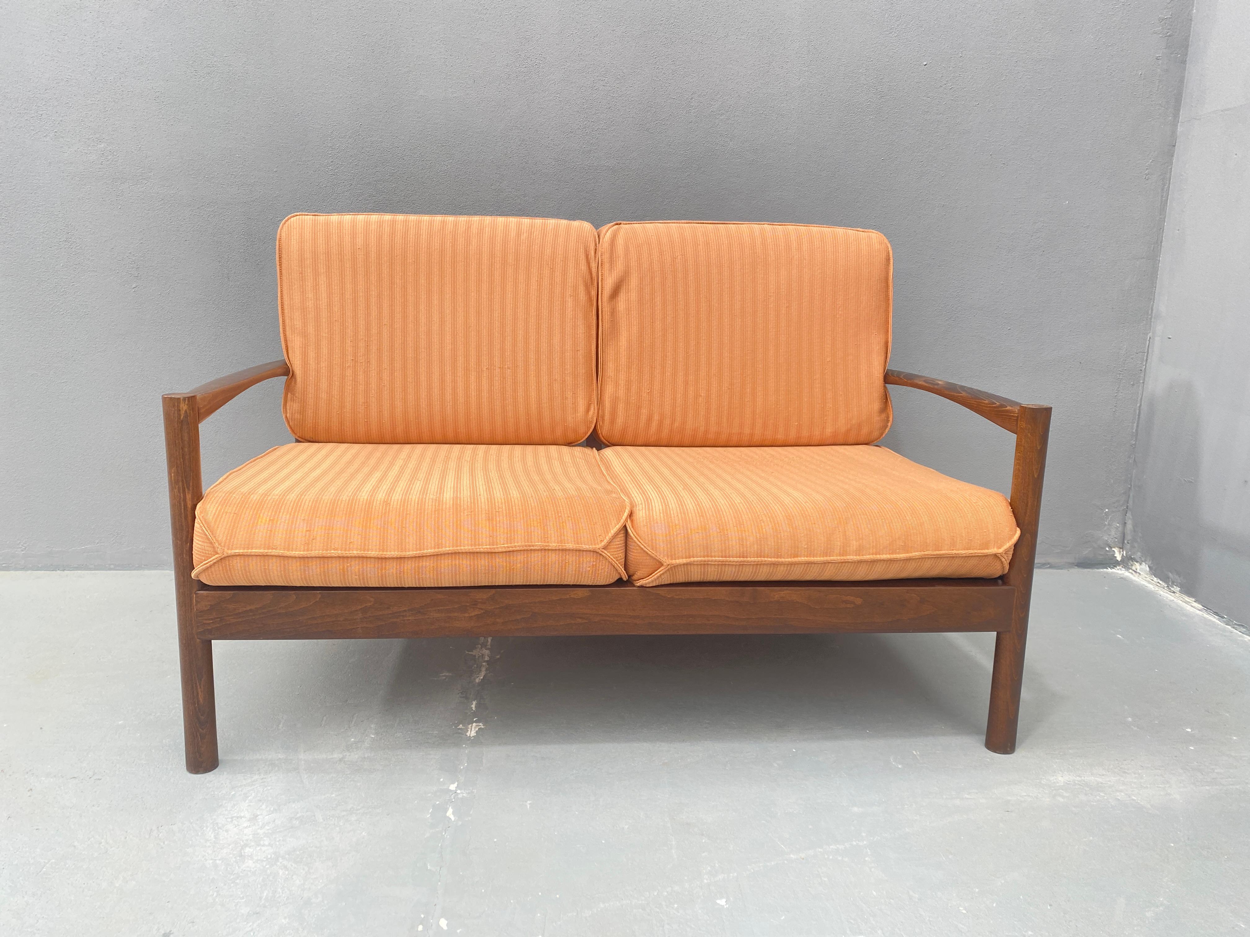 Questo divano a due posti è stato prodotto negli anni '80 in stile scandinavo. Il telaio in legno massiccio di faggio garantisce durata e stabilità. Il divano è dotato di cuscini imbottiti per la seduta e lo schienale, rivestiti in tessuto arancione