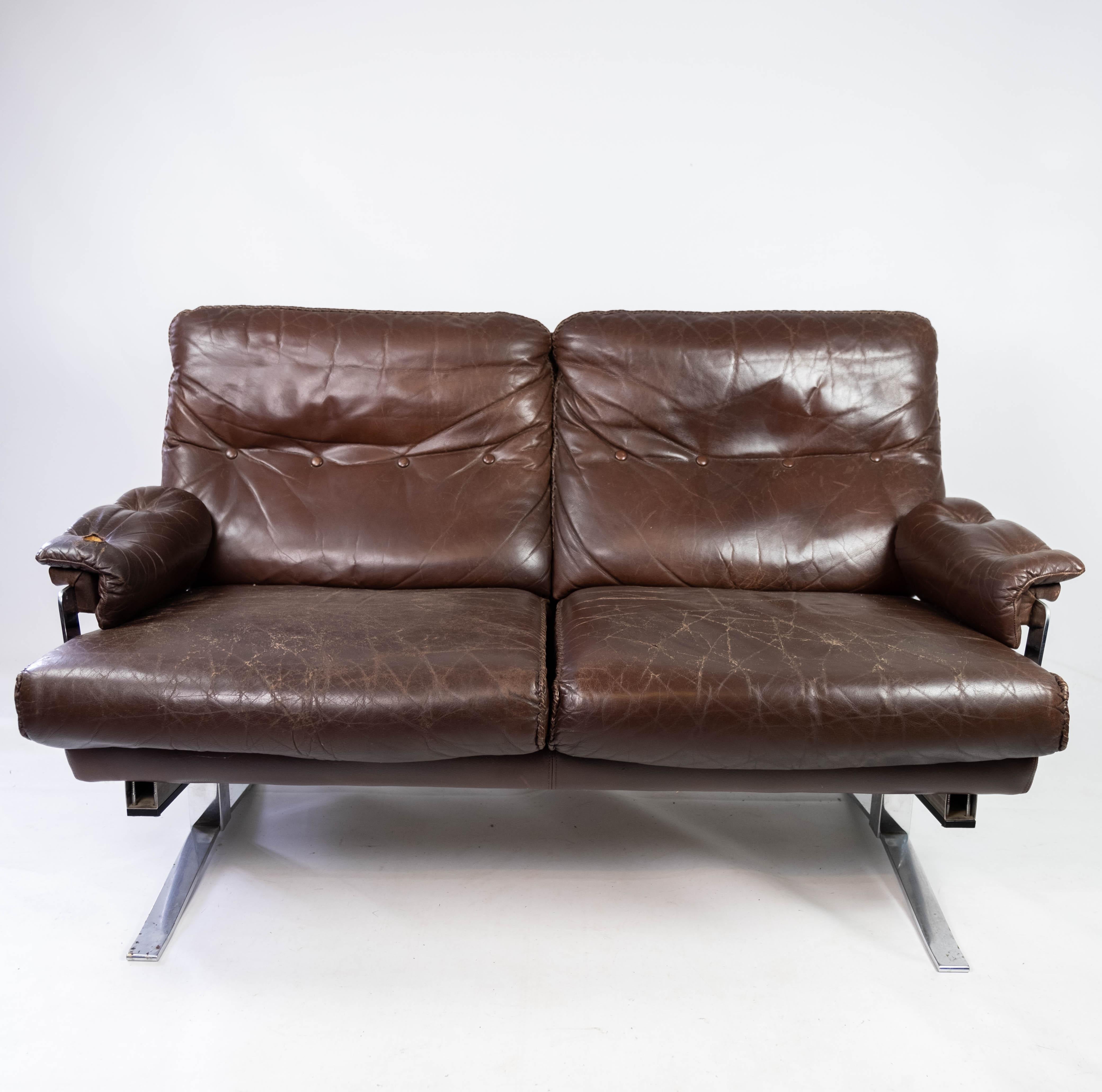 This two-seater sofa is a distinctive example of Arne Norell's design from the 1970s. With its upholstery of patinated leather and metal frame, the sofa exudes a stylish and modern aesthetic. Despite its age, the sofa is in nice used condition and