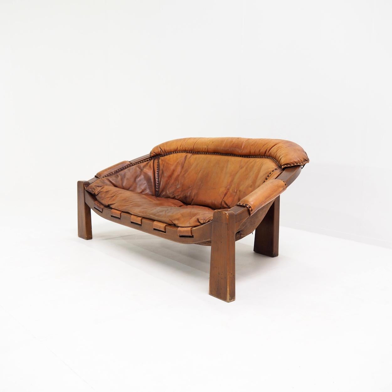 Beautiful two-seater sofa in the Brazilian brutalist style from the 1970s.

The sofa was designed by the Italian designer Luciano Frigerio and made and assembled in his studio.

The seat has an incredibly beautiful patinated leather with wear and