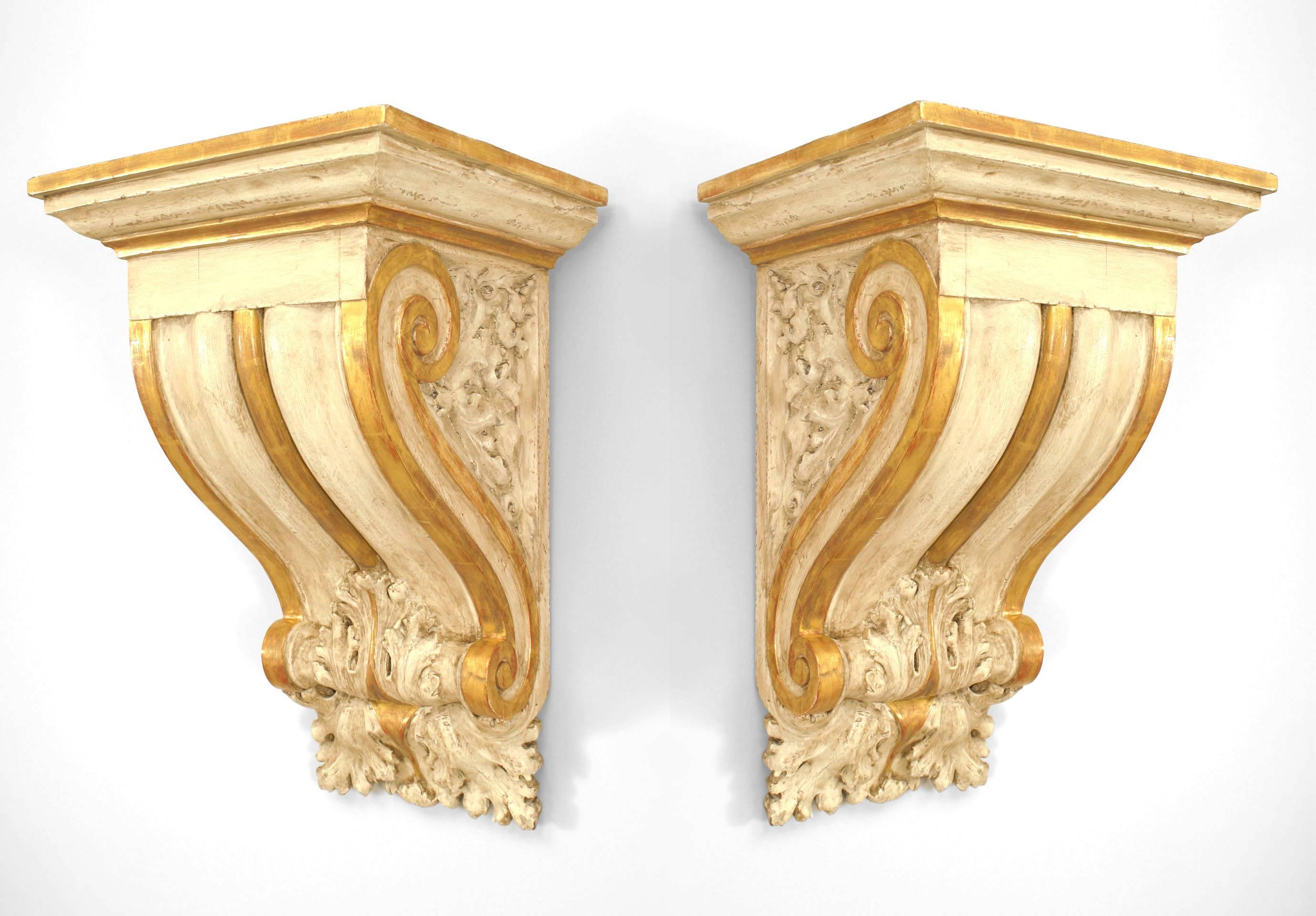 Pair of Italian Neo-classic cream painted and gilt trimmed carved wall bracket shelves with a scroll design and decorated with carved leaves (2-PRICED PER Pair)
