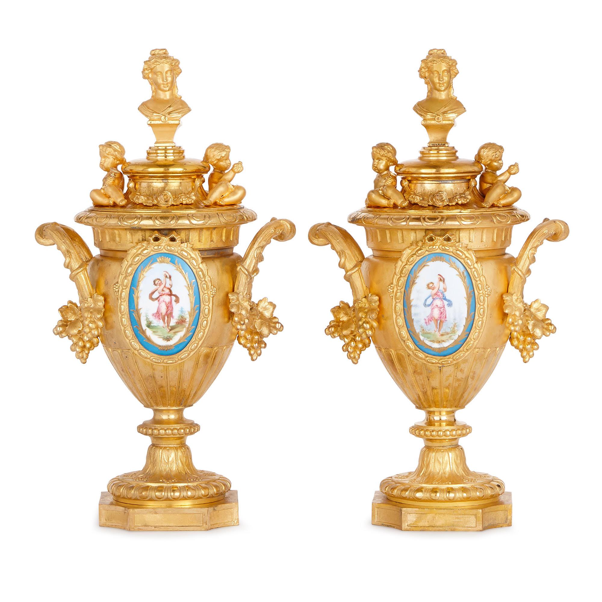 These vases were crafted in the late 19th century by the French sculptor, Phillippe H. Mourey. The items have been created from gilt metal and mounted with porcelain plaques, which is characteristic of Mourey’s work. 

The krater-shaped vases are