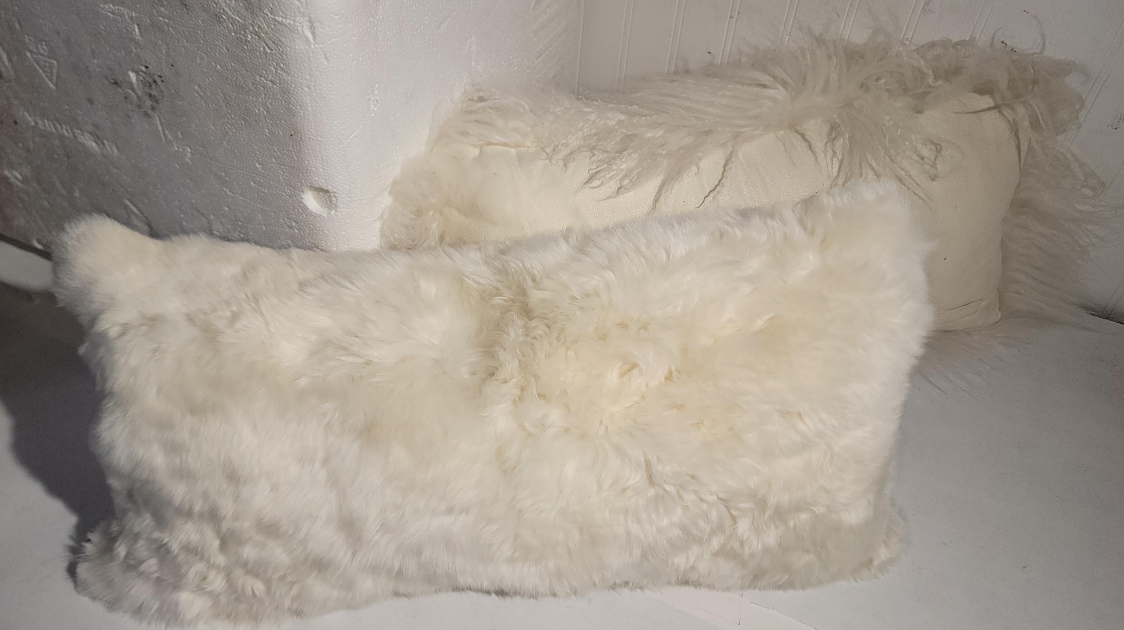 Two contemporary sheep skin white fur pillows. Both pillows are soft and supple. Very comfortable to the touch. Both pillows measure 22 x 10. 
