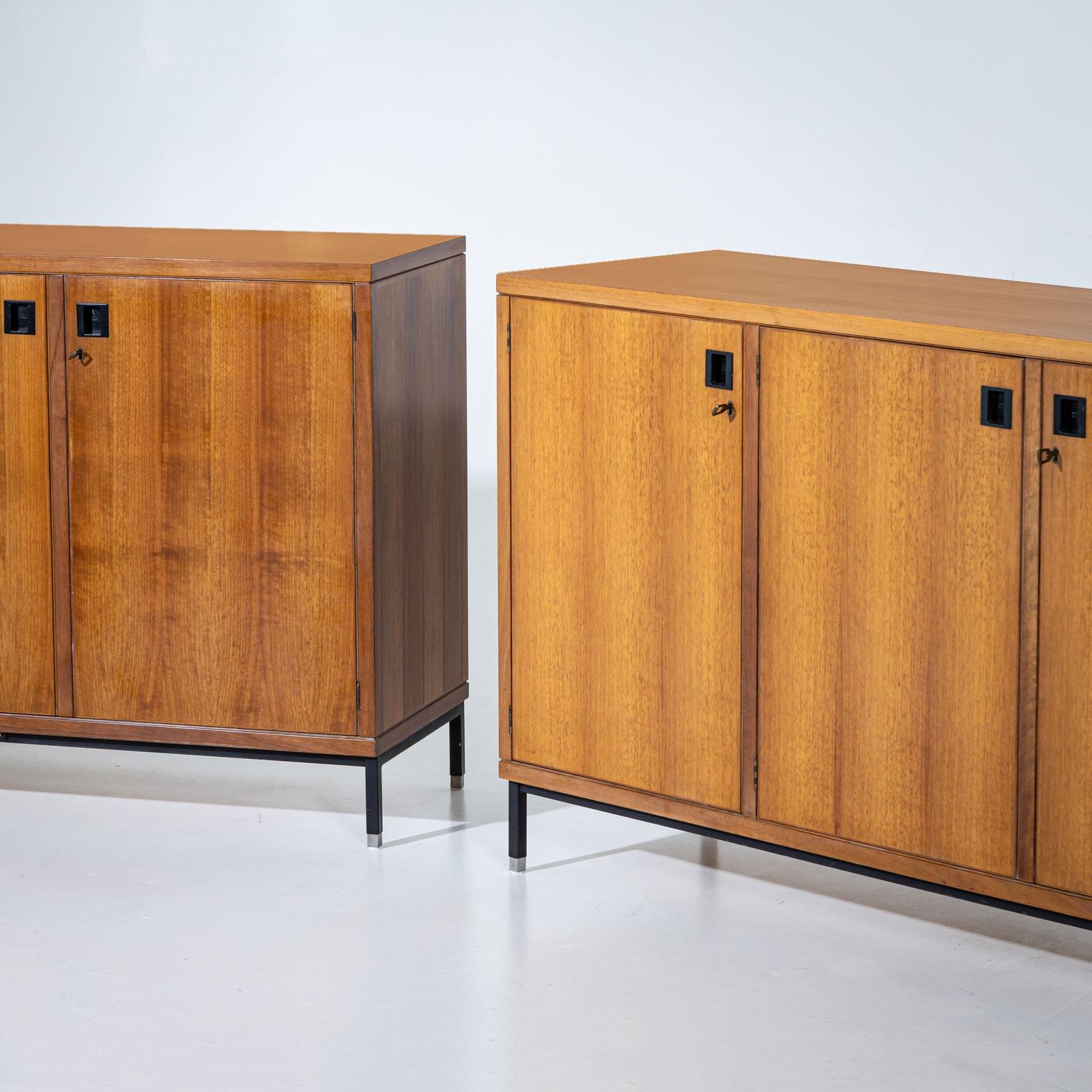 Two sideboards by Anonima Castelli Bologna, each featuring three doors with sleek black handles. The sideboards stand on elegant black metal legs with aluminum caps, accentuating their modern design. The interiors are fitted with shelves, providing