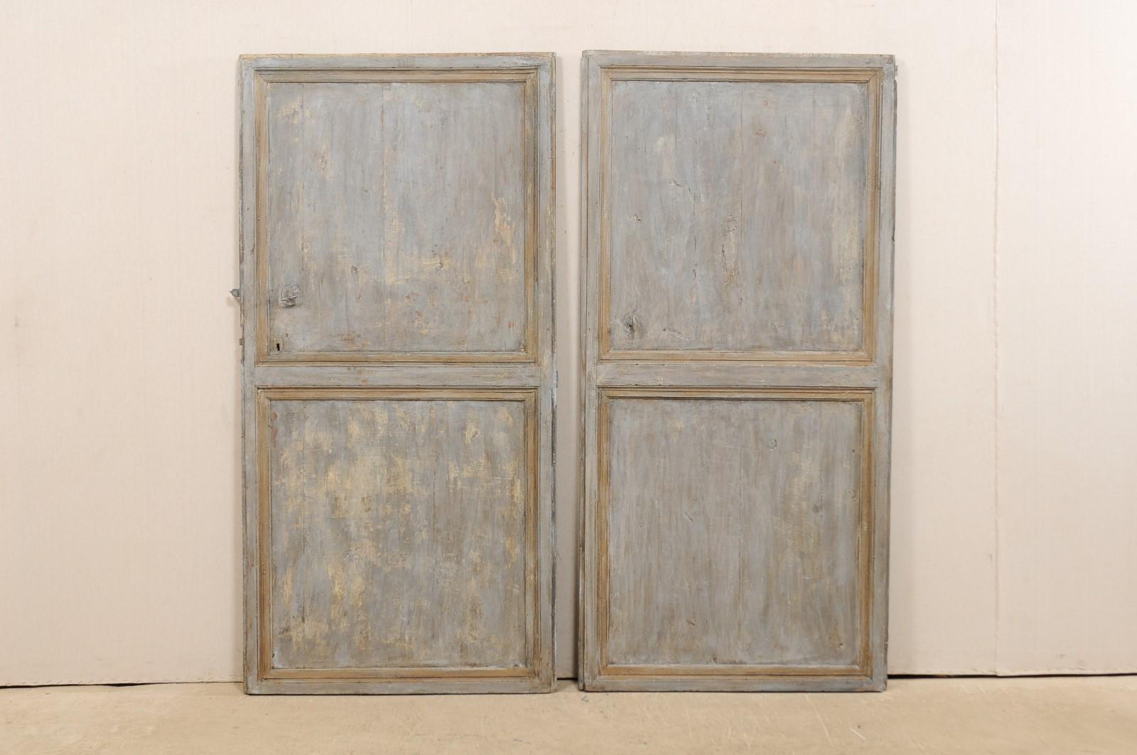 A set of 2 Spanish doors, both singles, from the 19th century. This pair of antique doors from Spain, are each adorned with a pair of recessed panels, square in shape, one topping the other, and divided with a raised framed molding between them. The