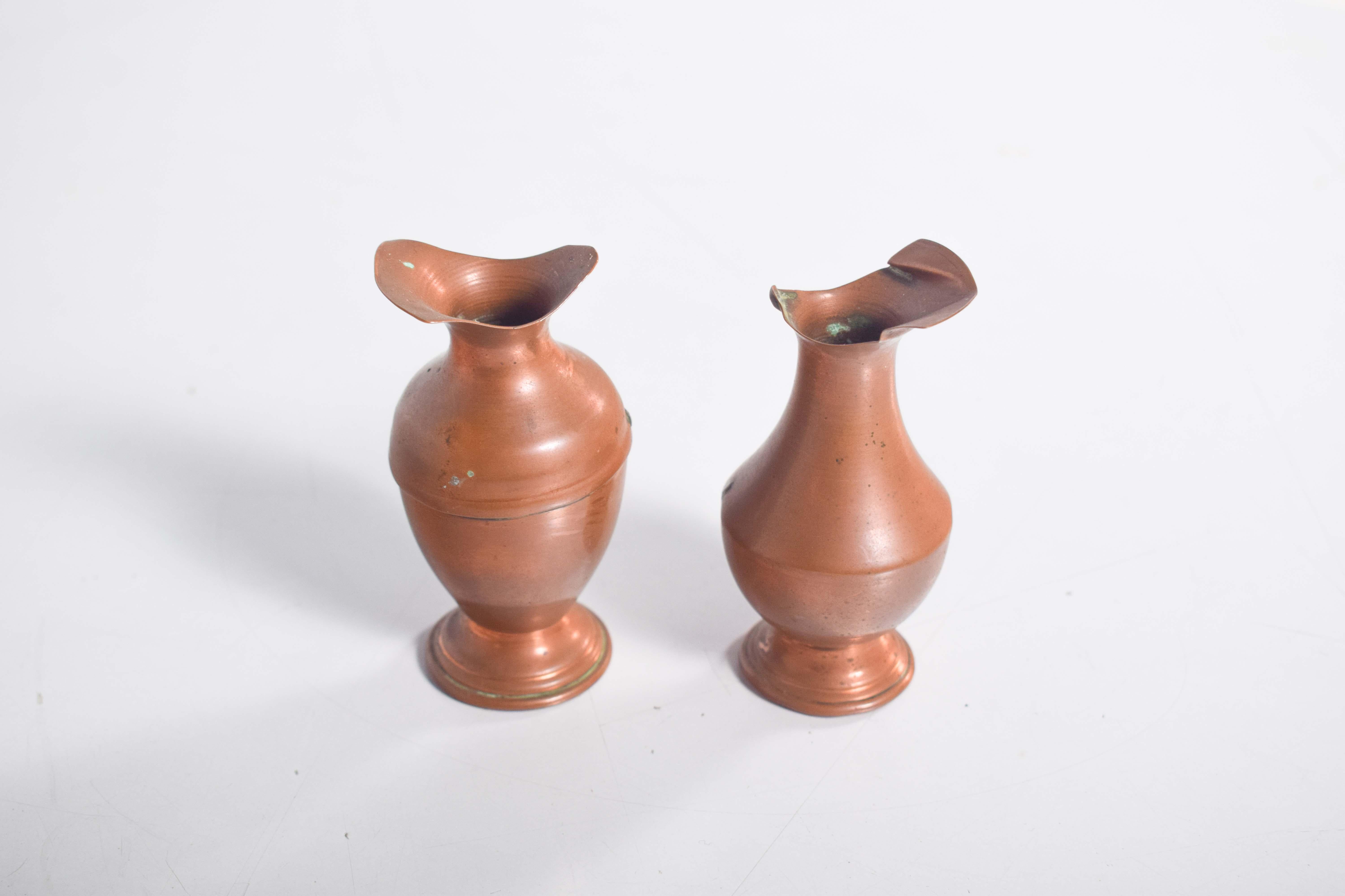 Questa coppia di piccole brocche in rame presenta un design semplice ma elegante, evidenziato dalle caratteristiche bocche ondulate che aggiungono un tocco di fluidità e fascino. Una brocca presenta un'importante scanalatura intorno alla sua pancia