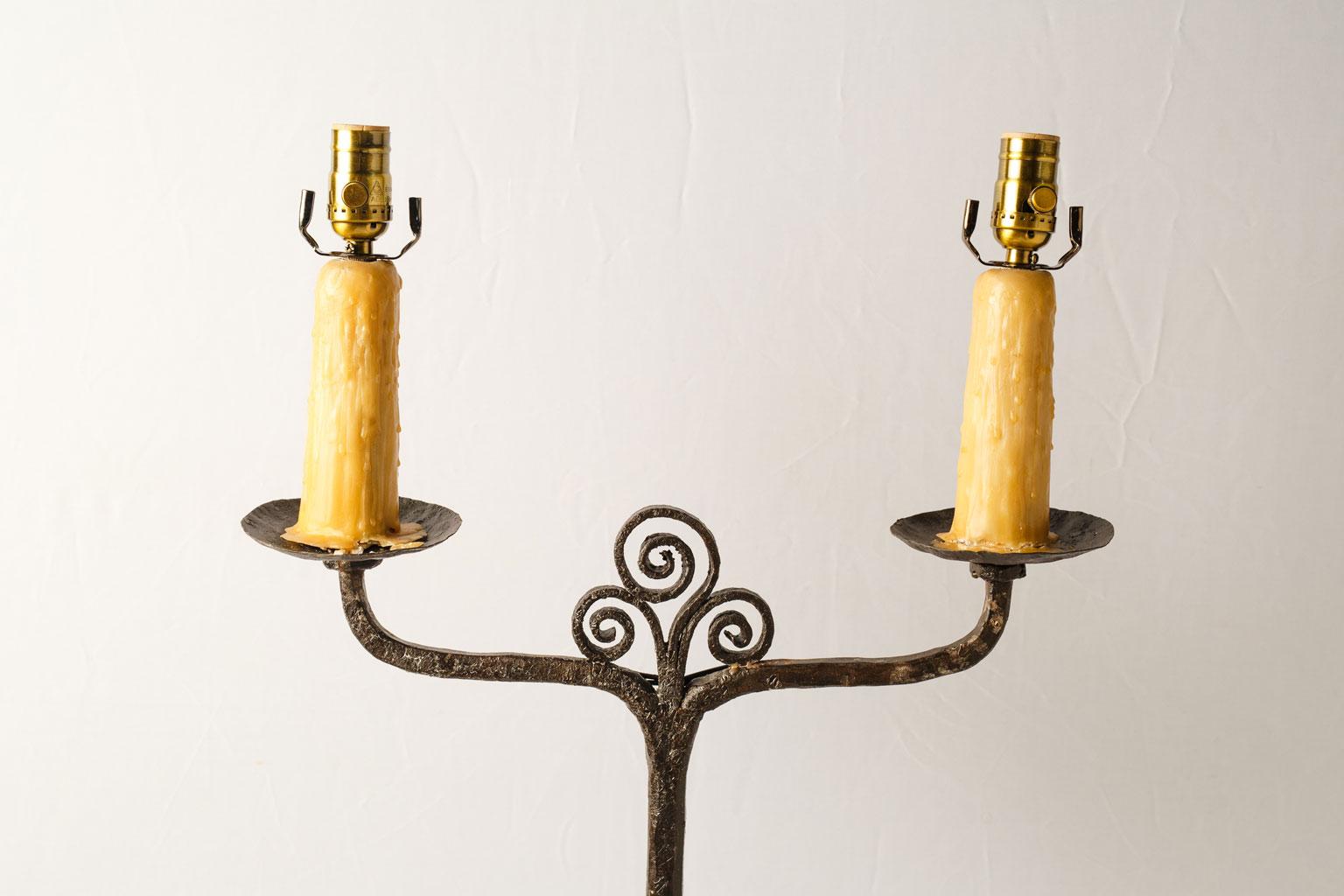 Two-socket candle stand floor lamp from France. A fine hammered, forged iron candle stand newly wired for use within the USA as a custom floor lamp. Two sockets accommodating medium-size (Edison) bulbs. Playful wrought iron swirl decoration and