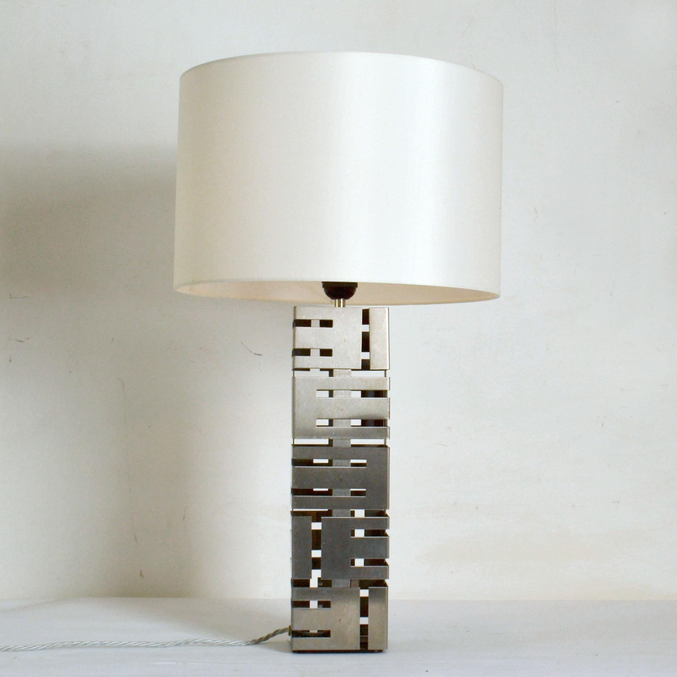 Two rectangular shaped brushed stainless steel lamps with a cut out design stainless steel panels on this pair of Laurel table lamp have two alternating heights. They come with ivory colour drum shades. 
Laurel lamp Mfg Company Inc. is a lighting