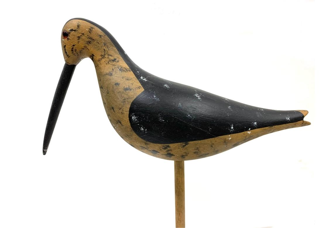Circa 1970's black and tan carved shorebird with glass eyes with a display stand. Incised signature on verso Stevens. 9 1/2