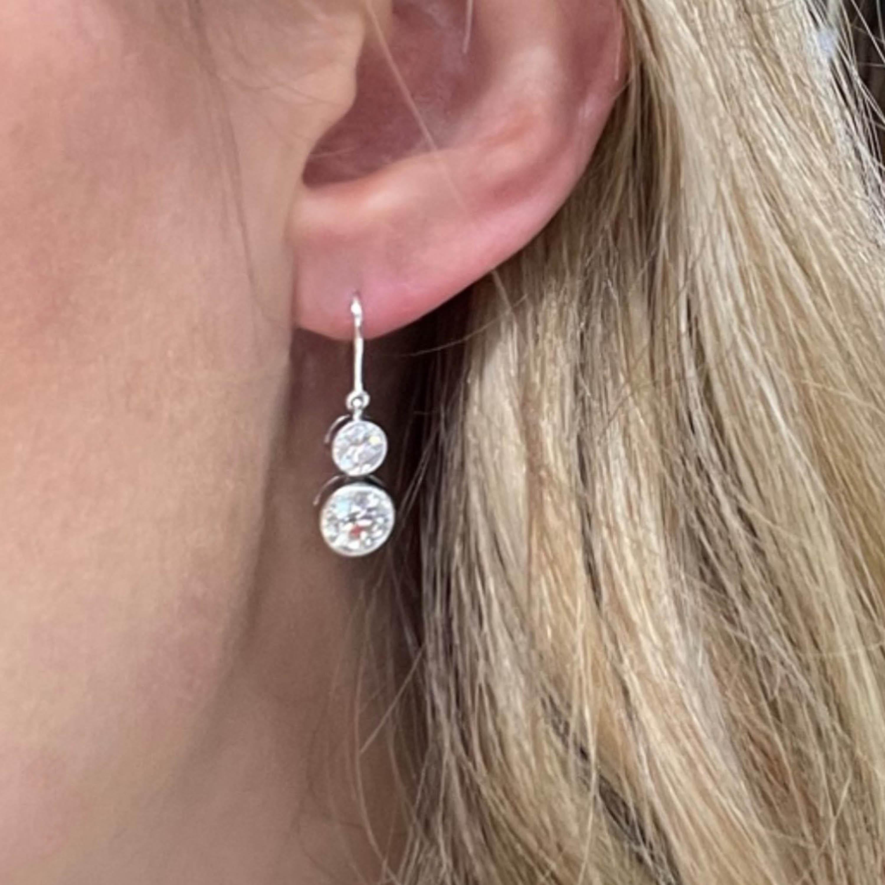 A pair of modern two stone diamond earrings, set with round diamonds weighing a total of 3.47 carats, the two top diamonds weighing a total of 1.16 carats, the two bottom diamonds weighing 1.18 carats and 1.13 carats respectively, grain and rub-over