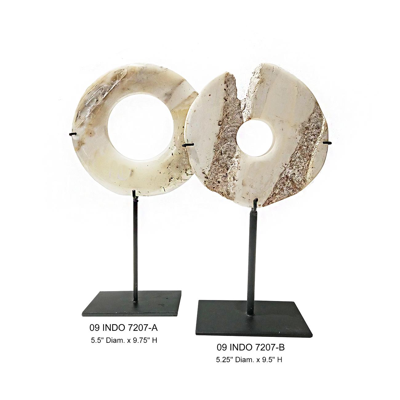Two beautiful stone disks, hand-carved in Indonesia. Mounted on black metal stands. 

The largest disk is 5.5 inches diameter, 2.5 inches deep and 9.75 inches high (mounted). The smaller disk is 5.25 inches diameter, 2.5 inches deep and 9.5 inches