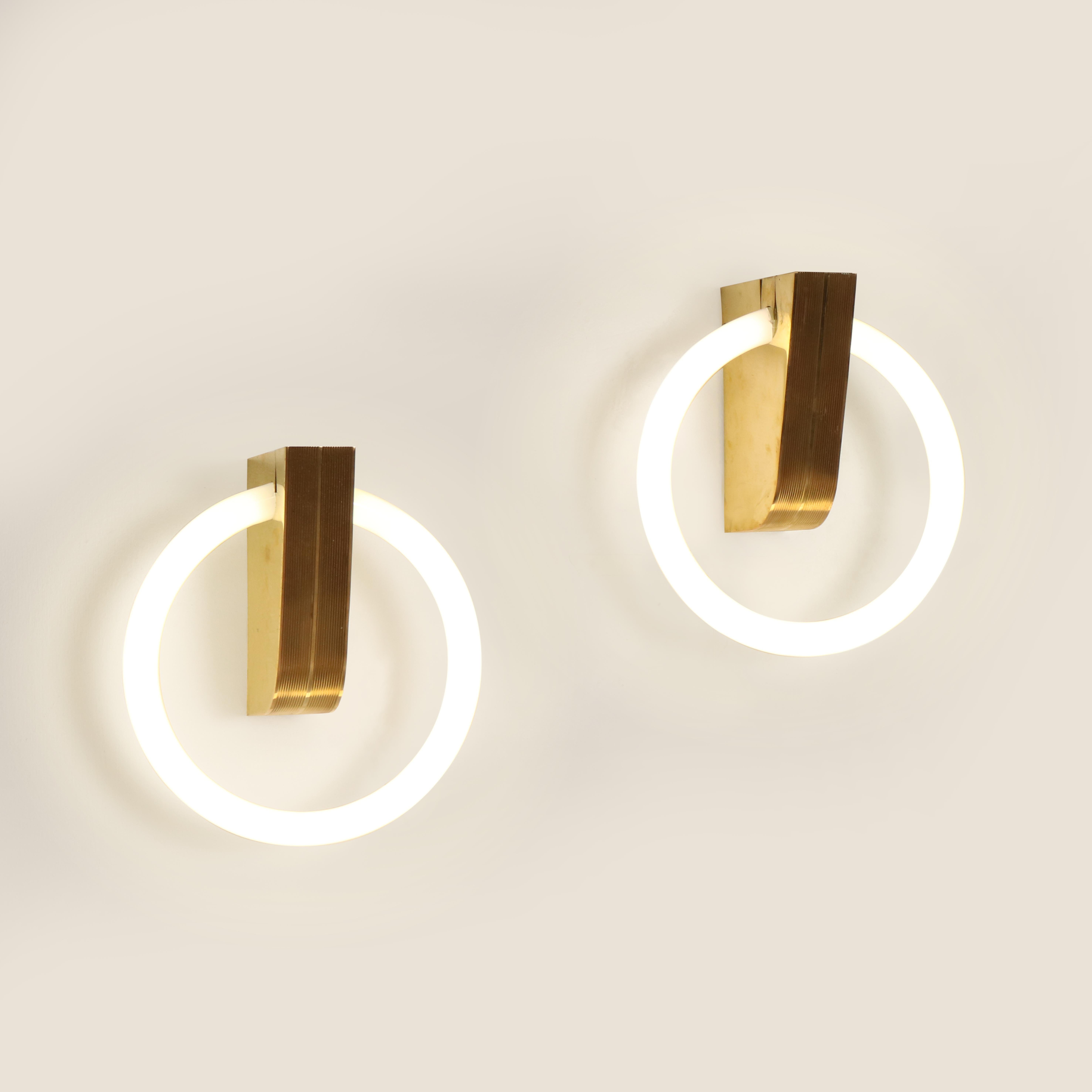 A very decorative set of two wall sconces that perfectly embodies the spirit of the 1970s with experimentation with shapes and geometries. The brass and striated brass structure encapsulates in a compact body the essence of the wall lamp by